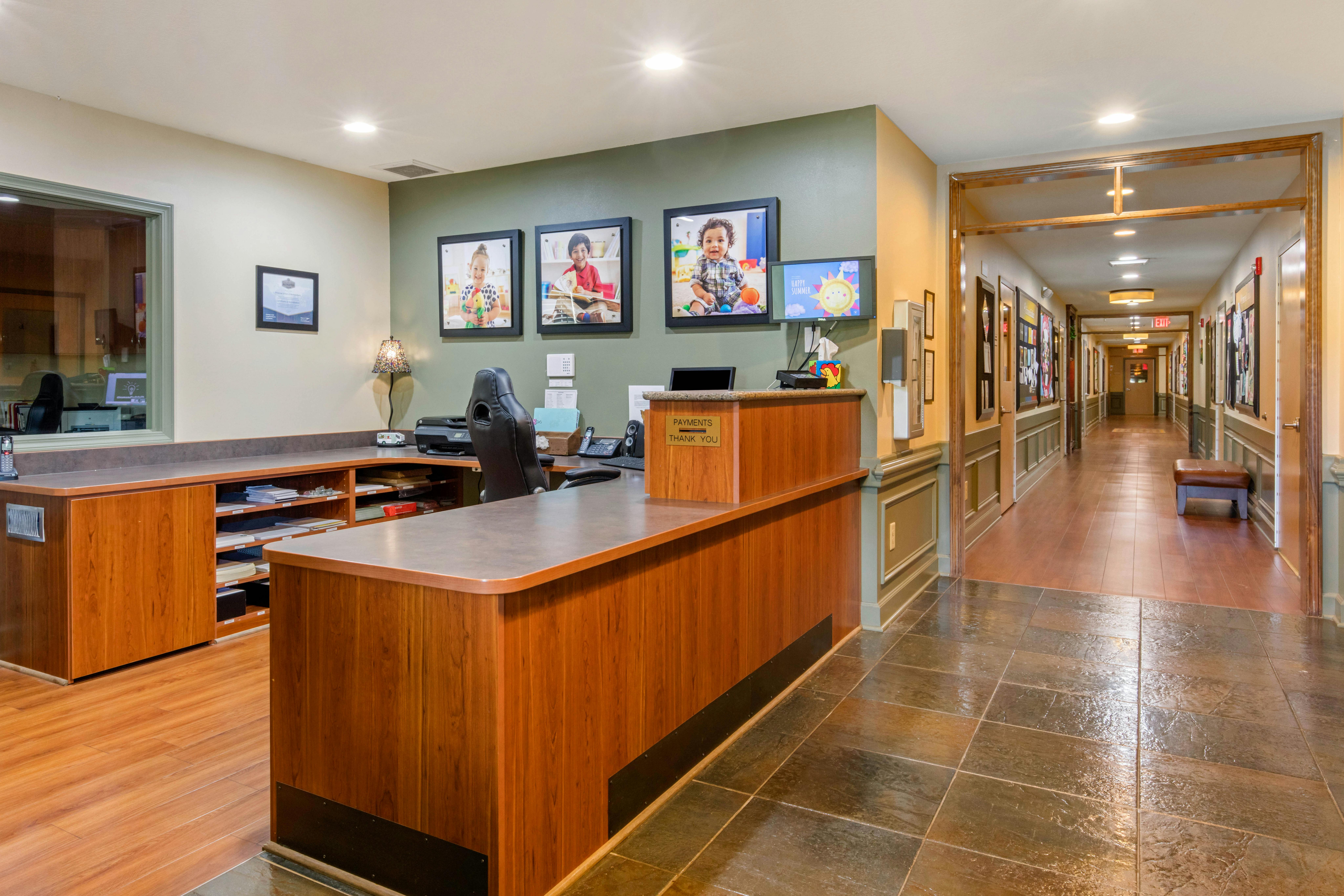 Reception desk with child photos on the wall and a long hallway