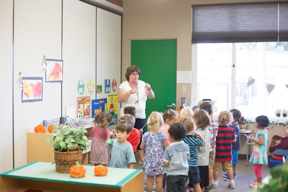 Person speaking to a group of children in a classroom
