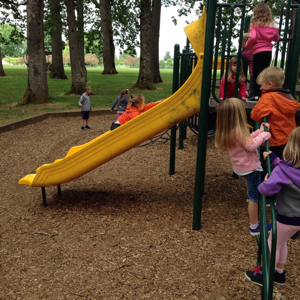 Children playing on a yellow slide and climbing structure at a playground