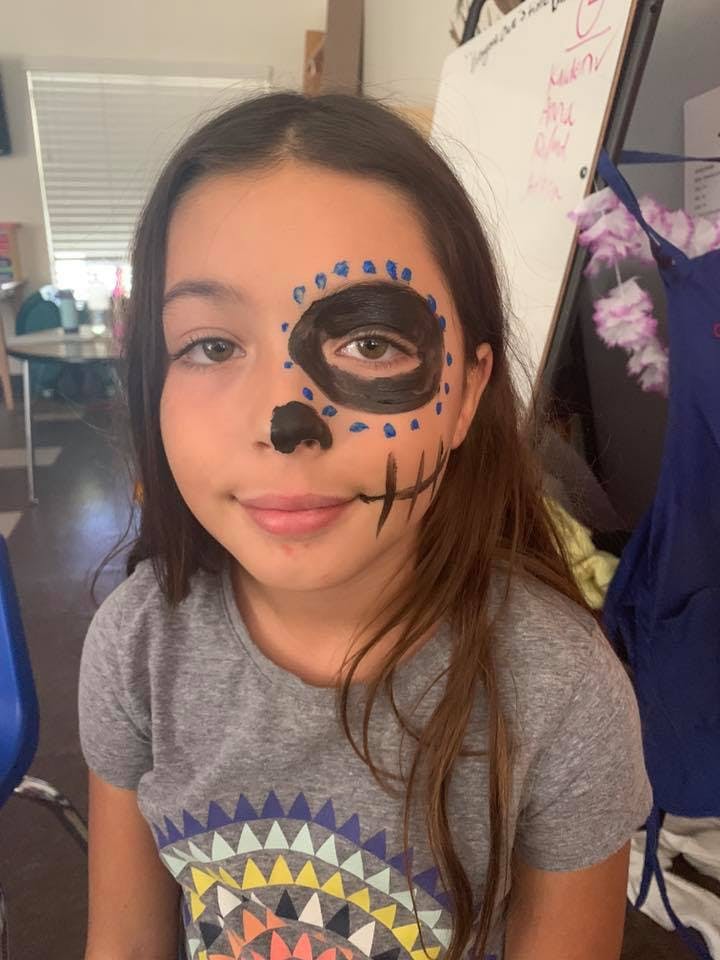 Child with half of their face painted like a skull