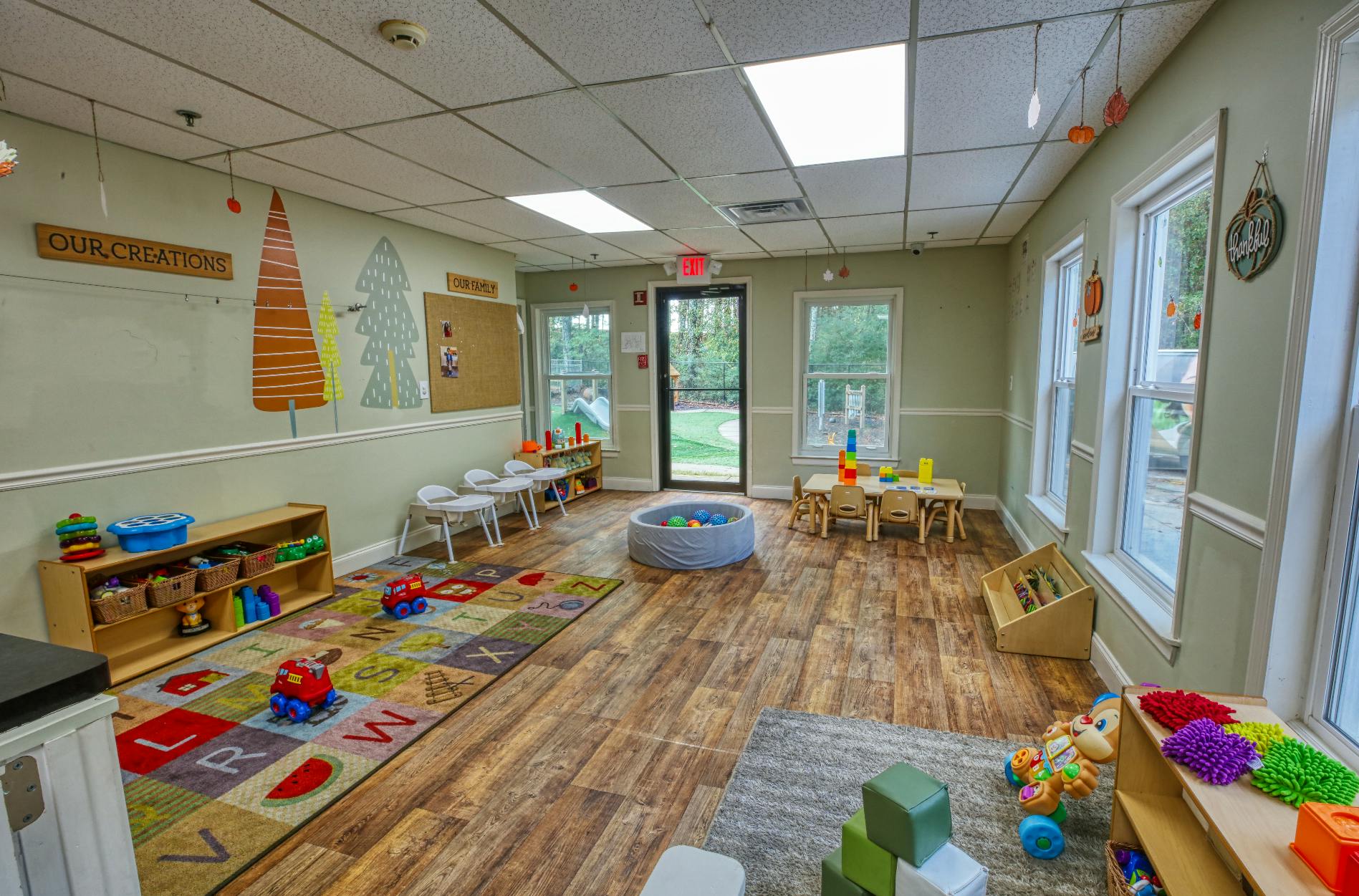 A colorful childcare classroom with toys, small tables and chairs, and a ball pit