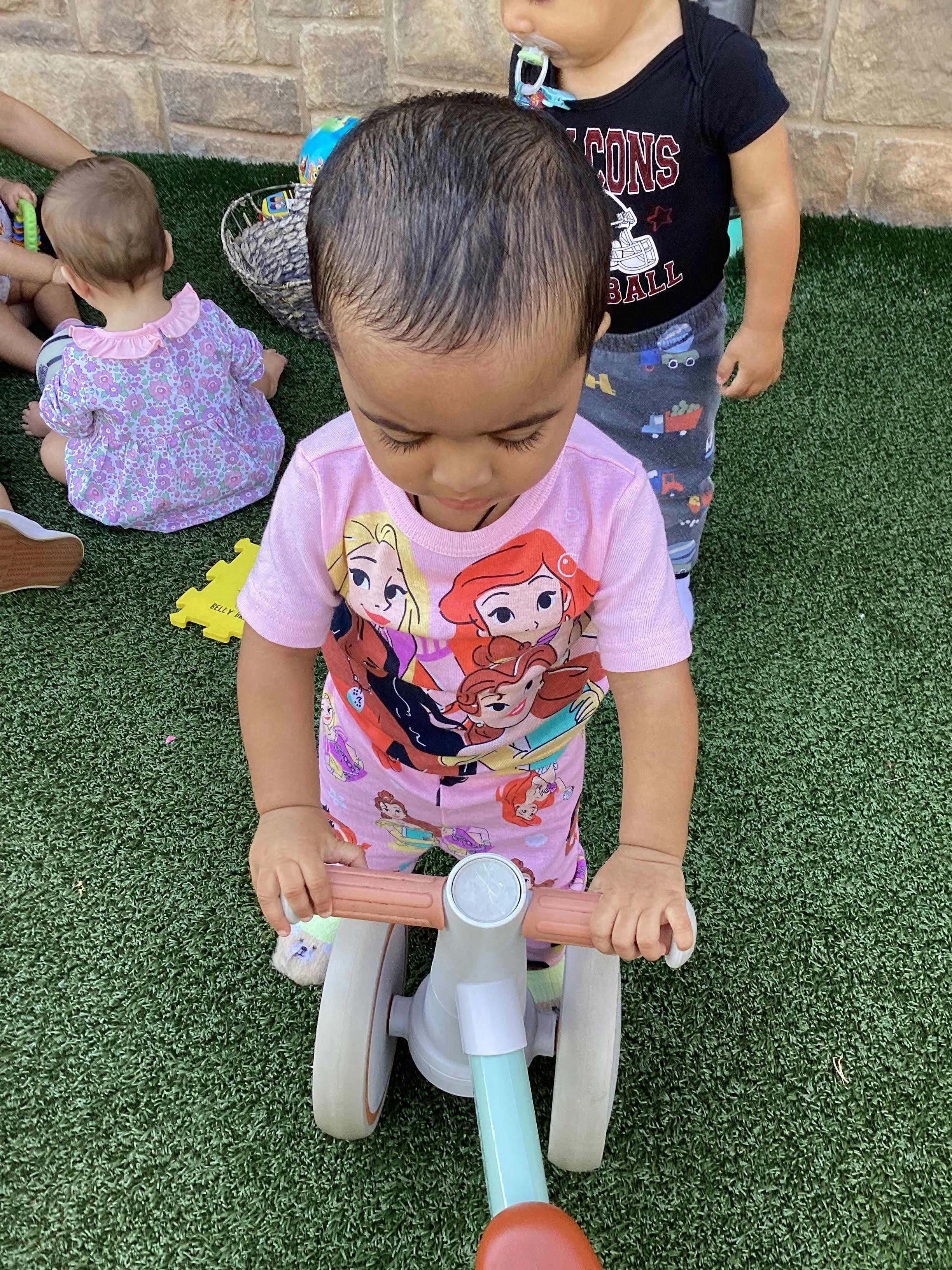 Child on a small tricycle with other children in the background