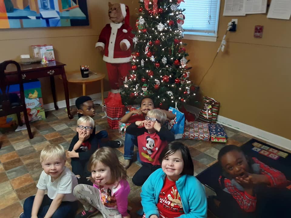 Group of children sitting on the floor in front of a Christmas tree