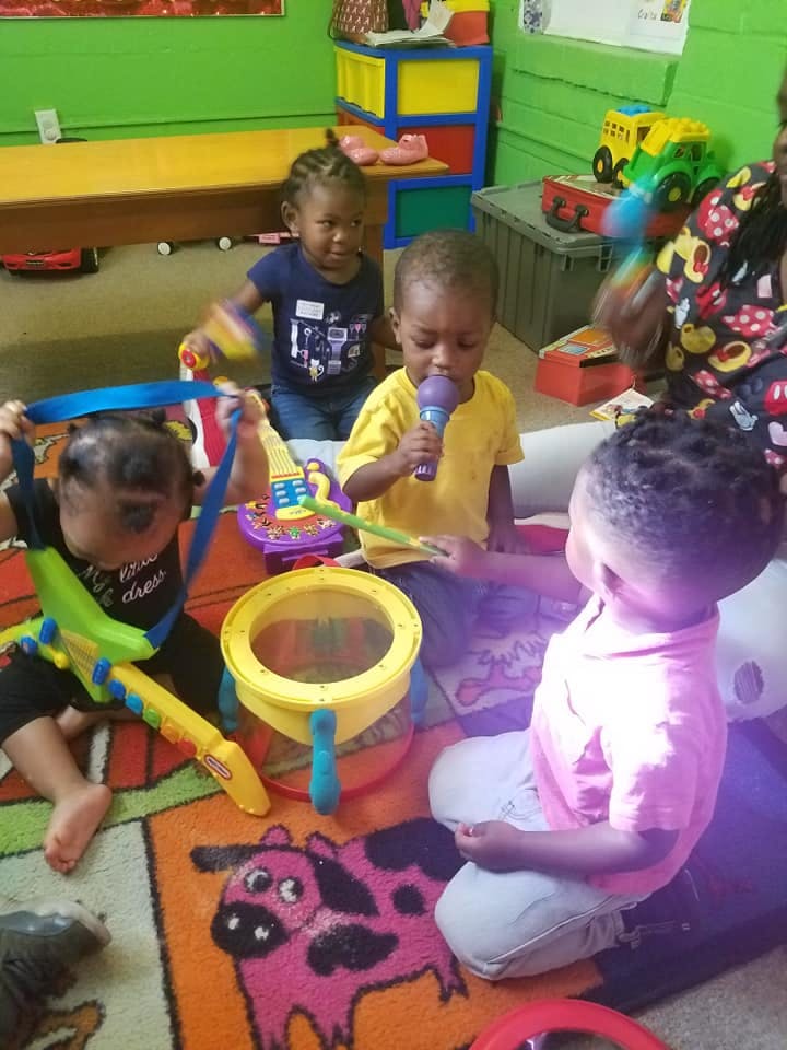 Children playing with musical toys on a colorful rug