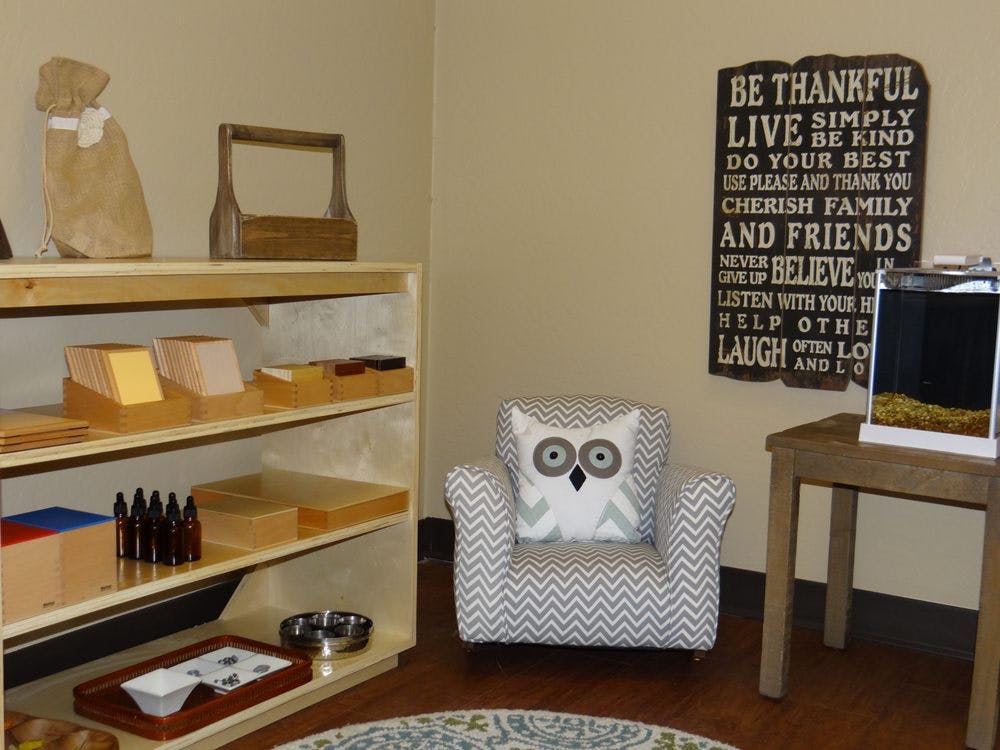 Montessori classroom with shelves, child-sized armchair, and wall art