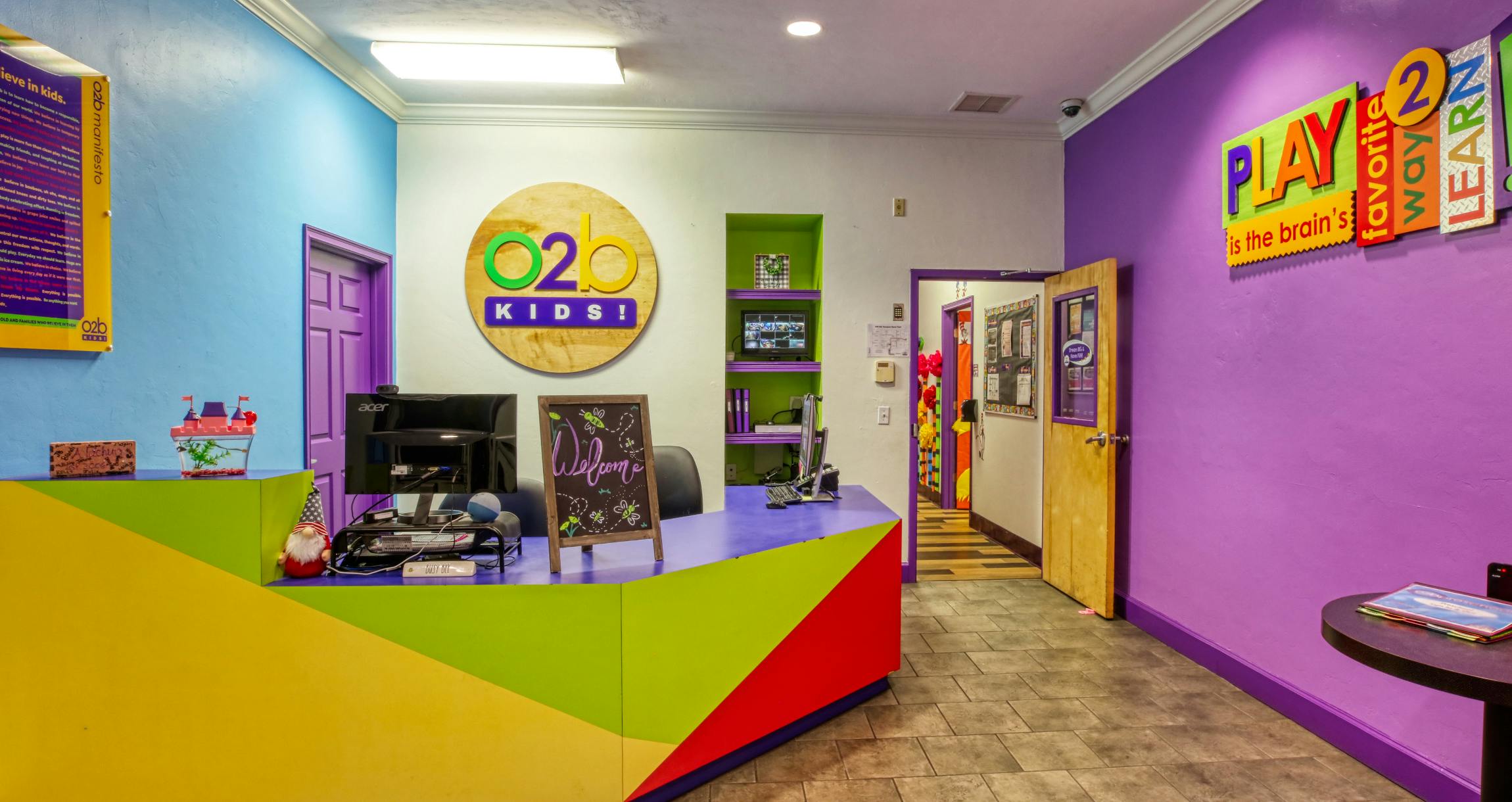 Colorful reception area of a kids' center with a "Play is the brain's favorite way to learn" sign