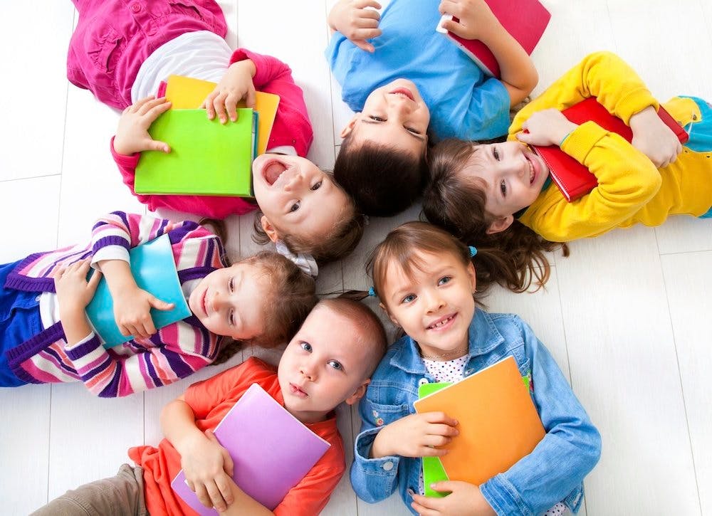 Group of children lying on the floor in a circle holding books