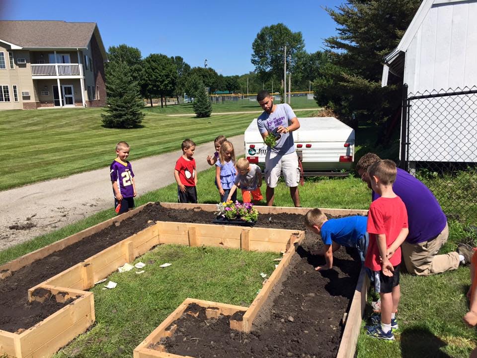 Adults and children planting in a raised garden bed