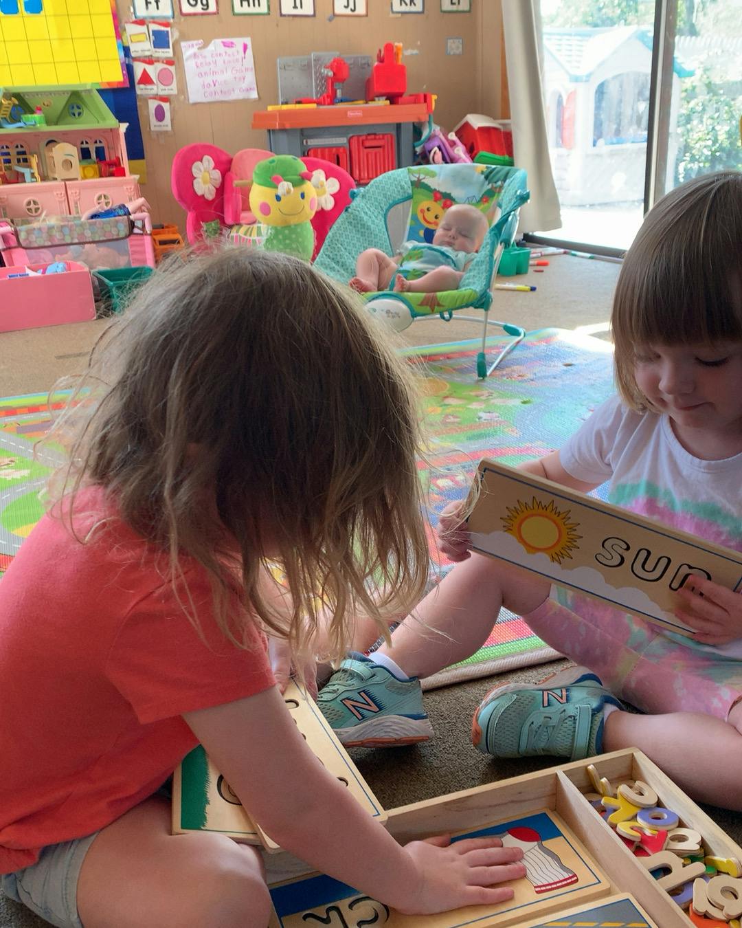 Two children playing with wooden puzzles on the floor