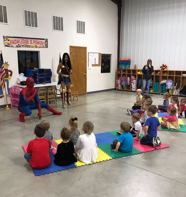 Person in superhero costume and person dressed as Wonder Woman with children