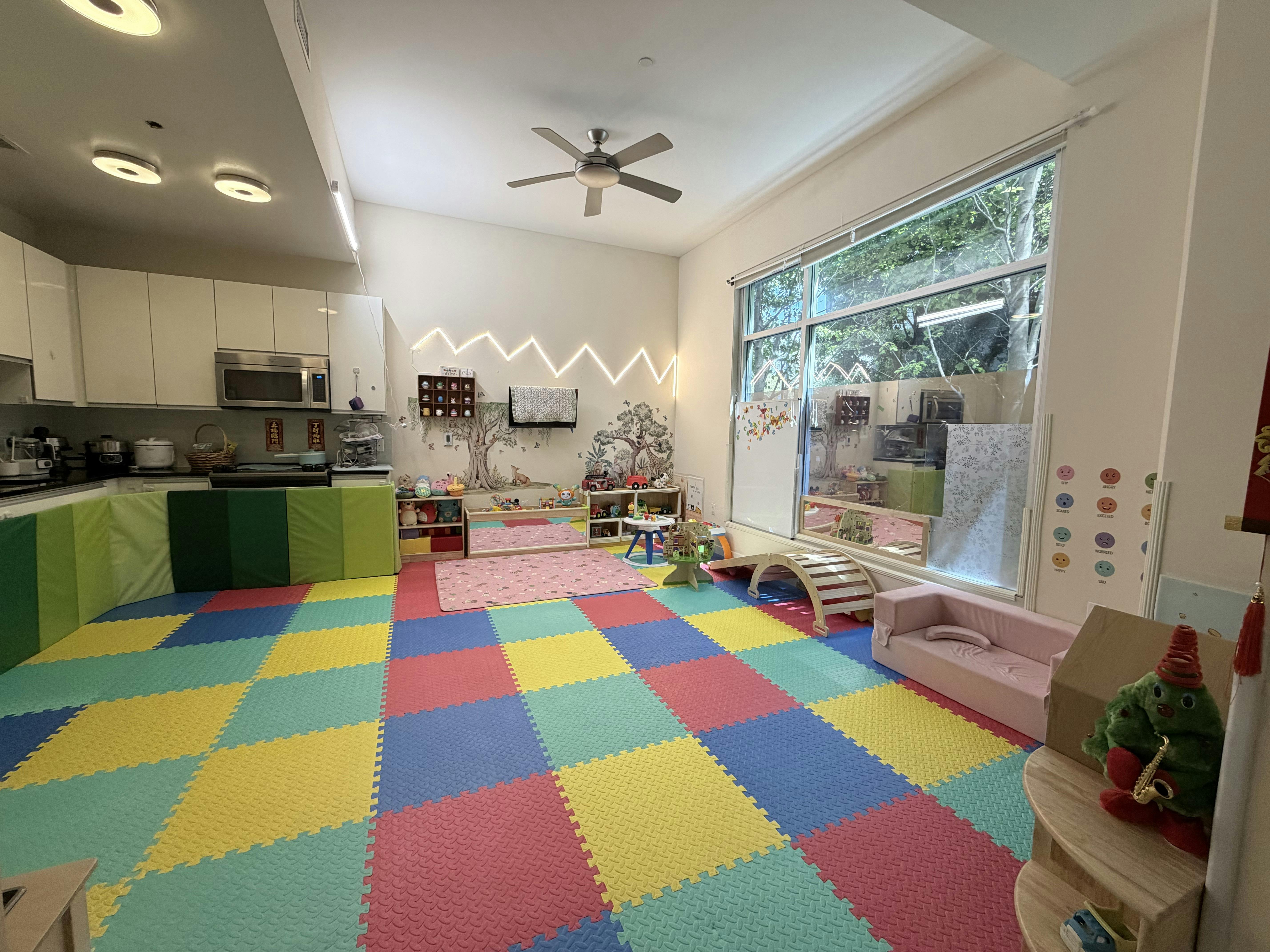 A playroom with colorful foam mat flooring, toys, and a large window