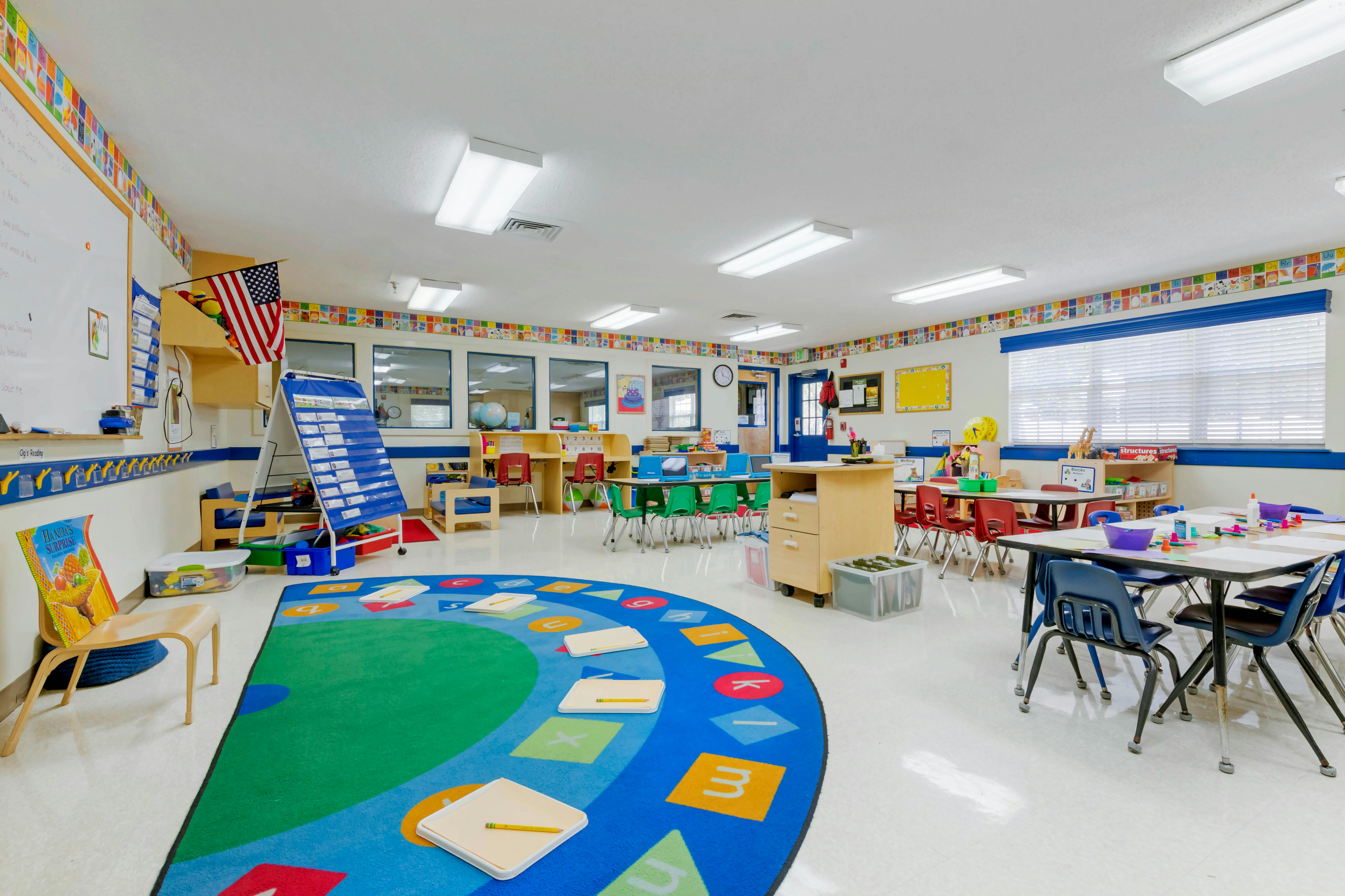 An empty early childhood classroom with colorful decor and small tables