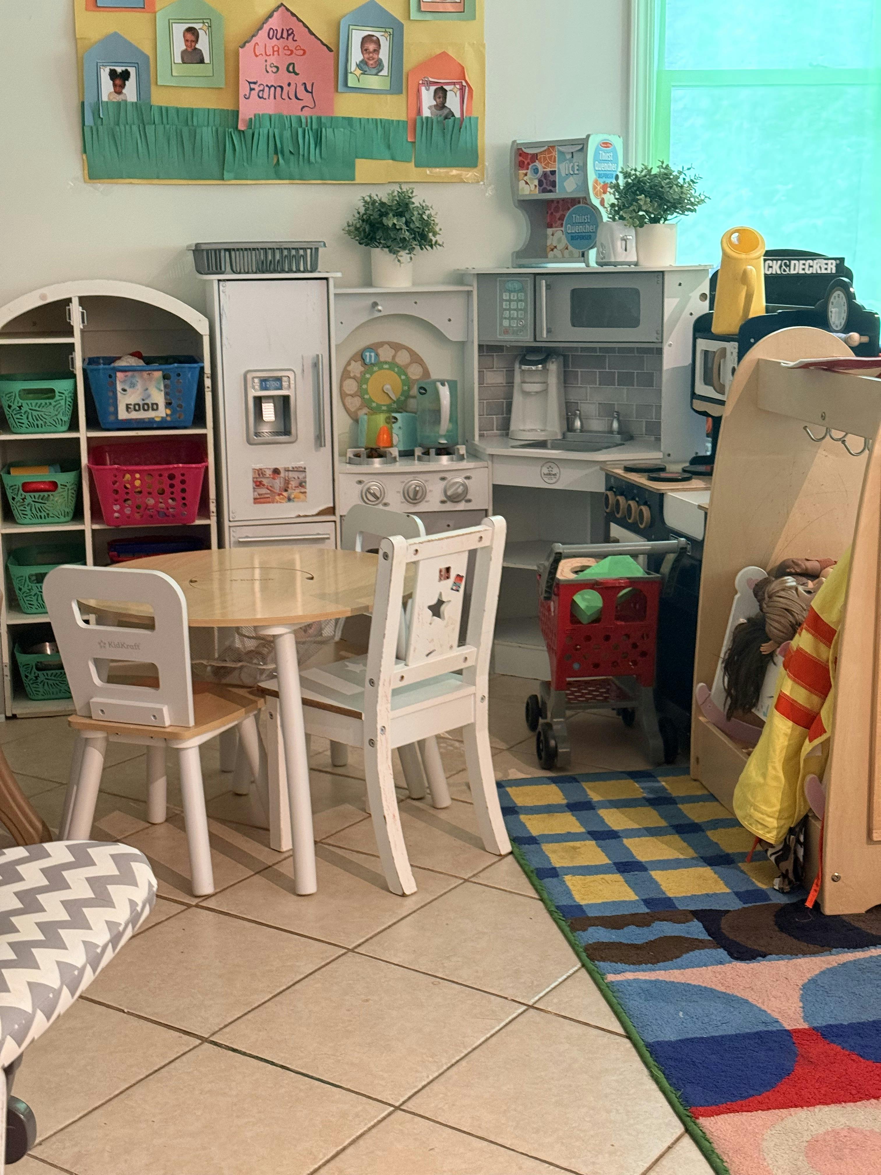 Childrens play kitchen area with toy furniture and table in a classroom