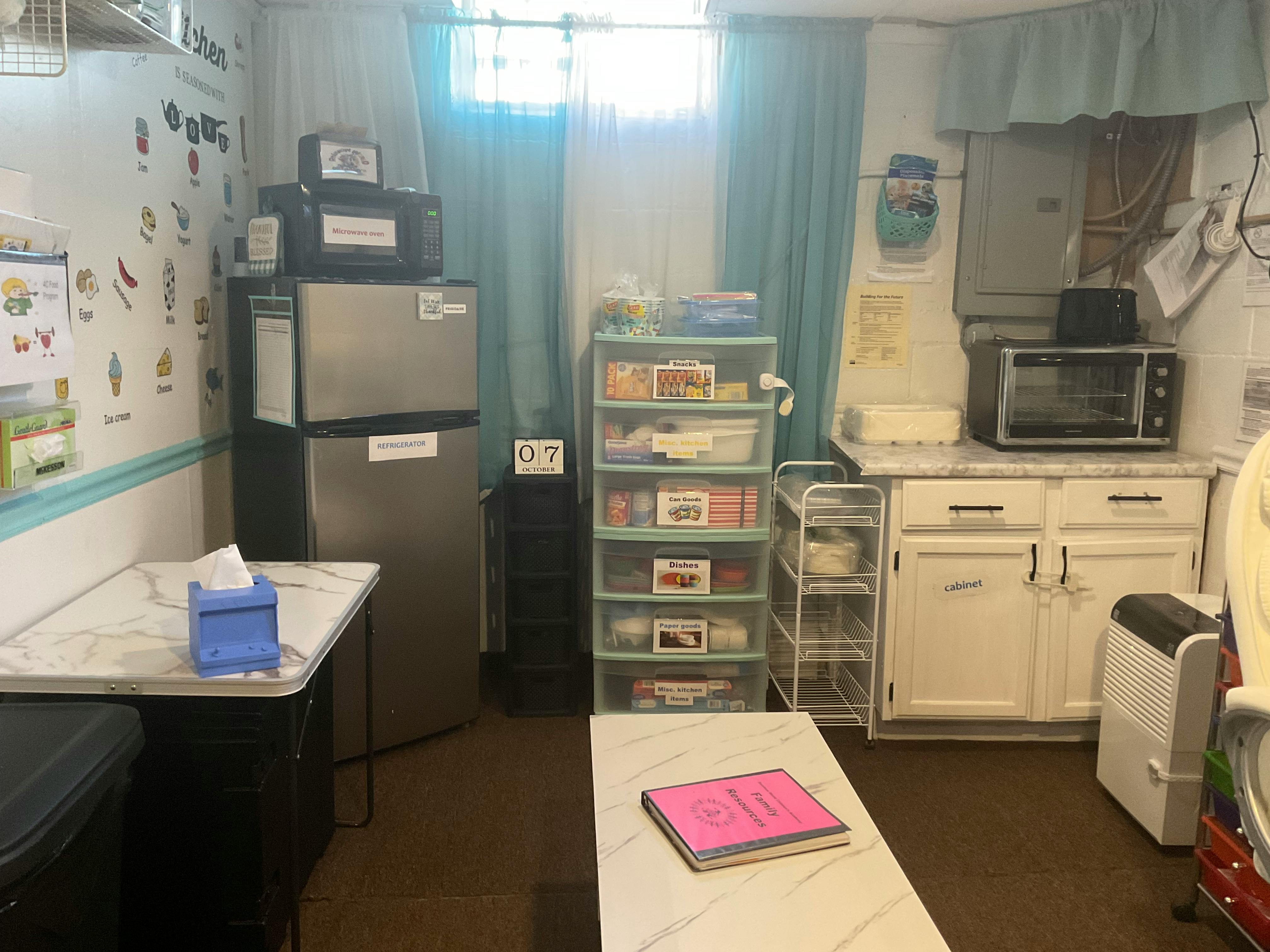 Kitchenette area with a refrigerator, shelving units, and a counter with cabinets