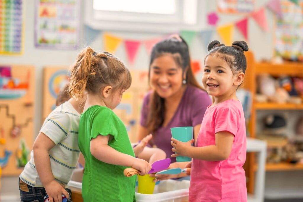 Adult and children playing with toys in a classroom