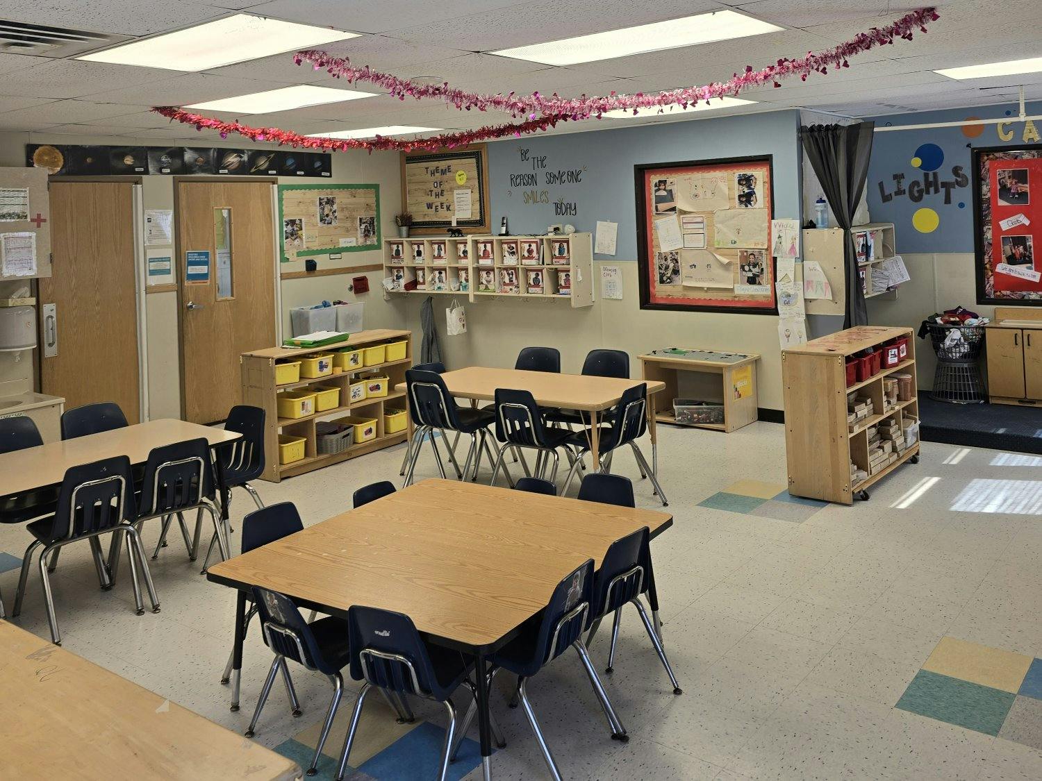 Classroom with small tables and chairs, storage shelves, and decorated walls