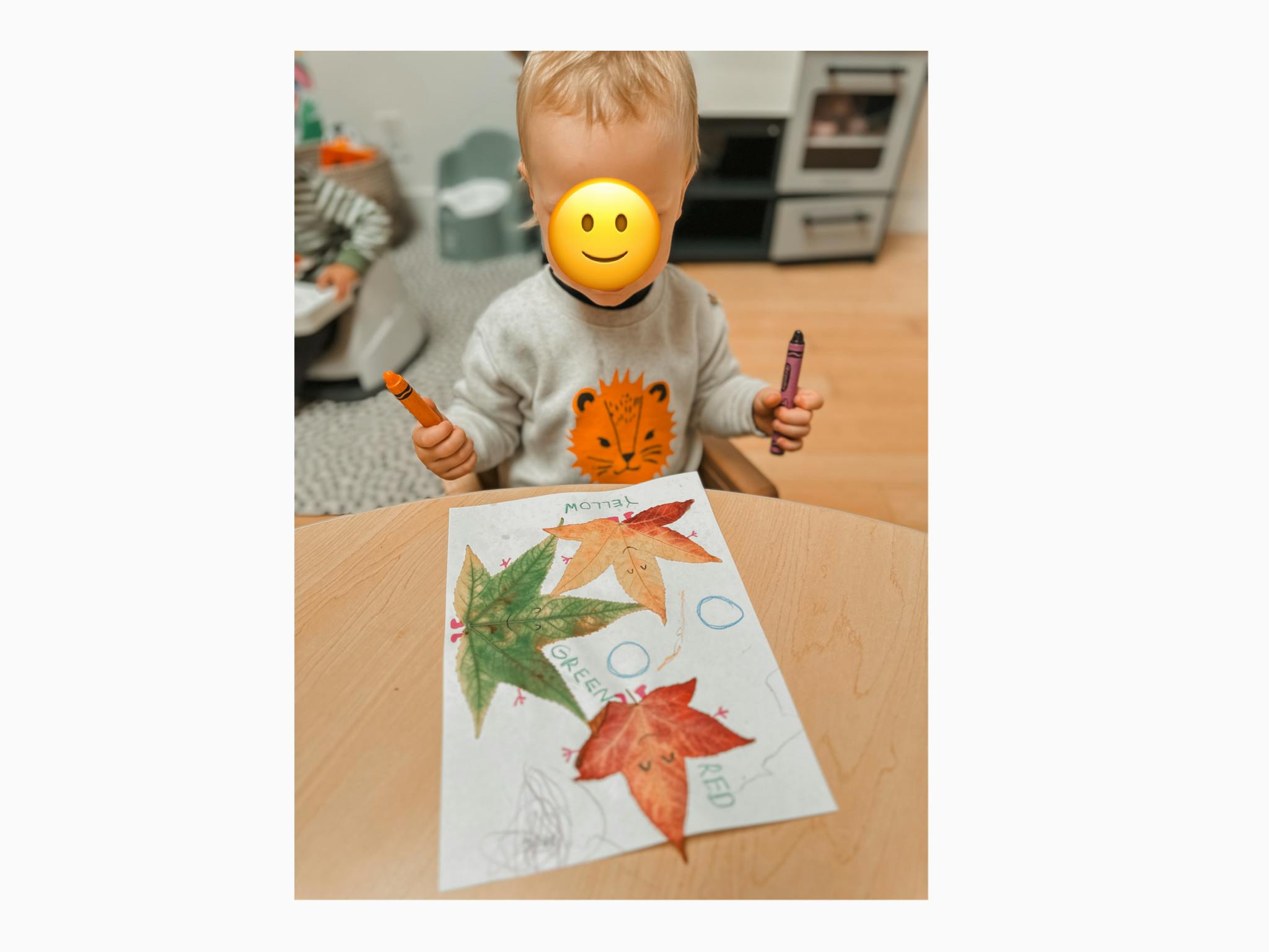 Child holding crayons over a drawing of leaves