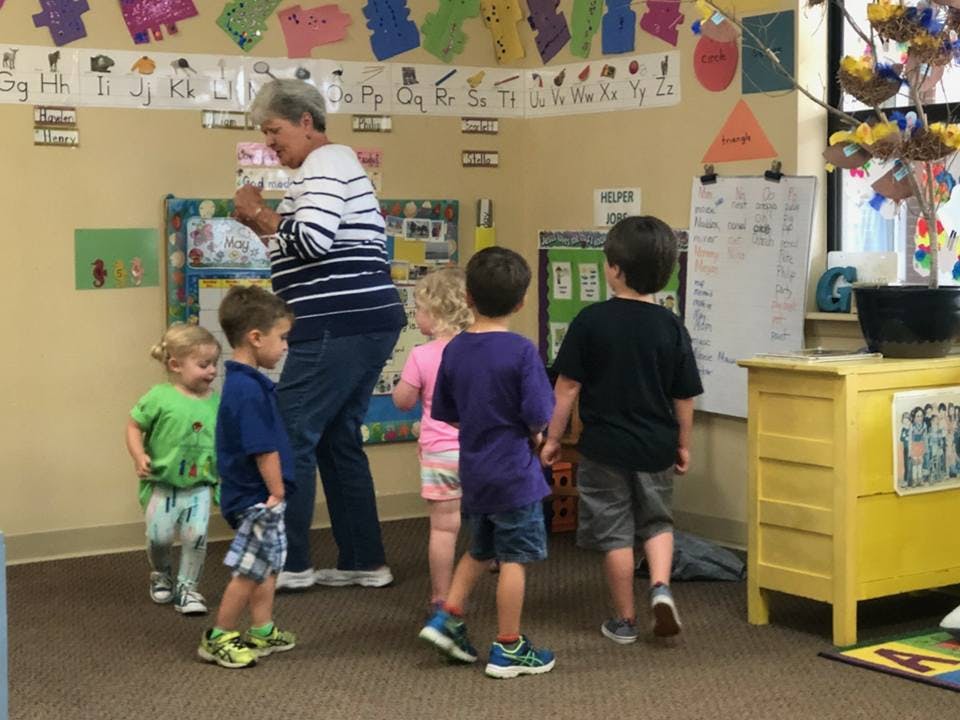 Adult person with several children in a classroom