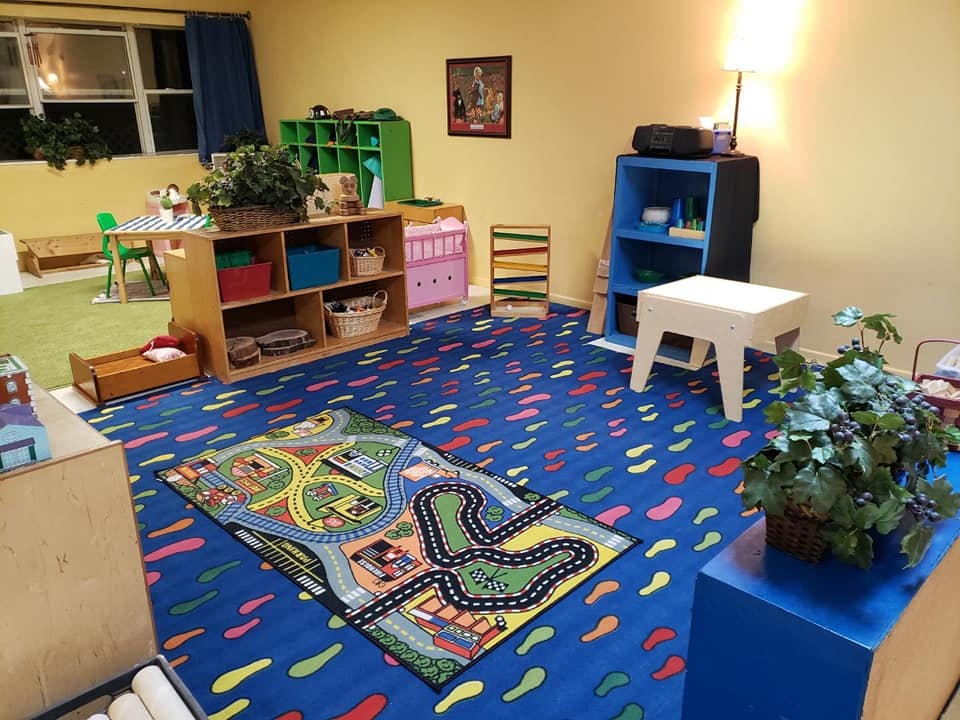 Playroom with blue carpet, toy rug, and shelves