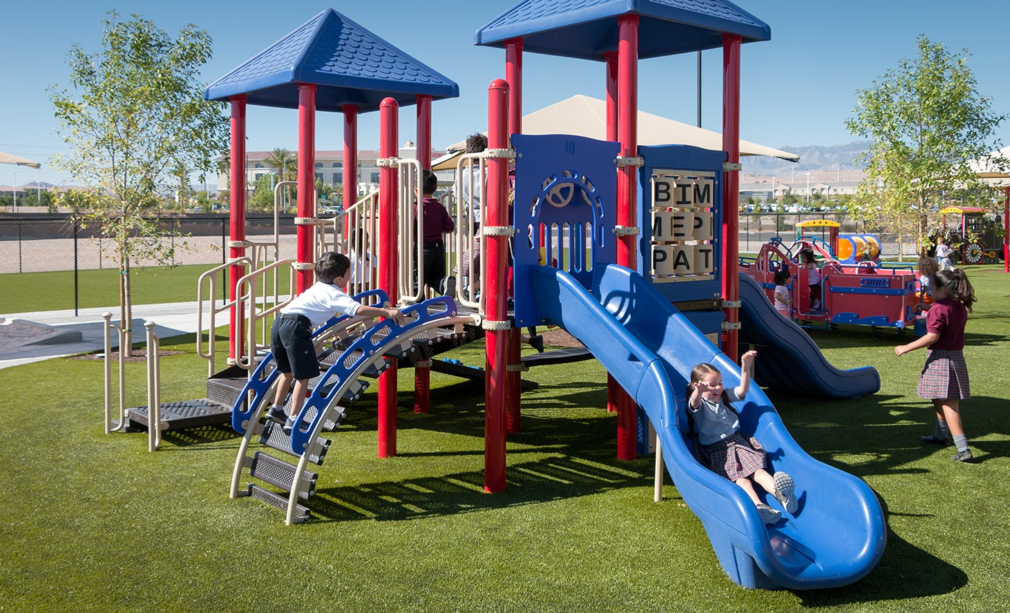 Children playing on a playground structure with slides and climbing structures