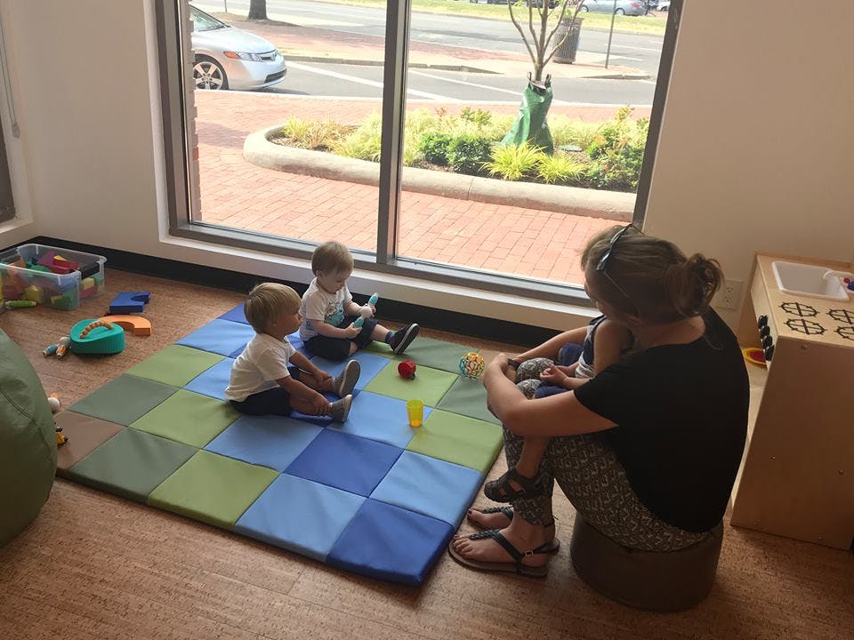 Adult and two children sitting on a playmat