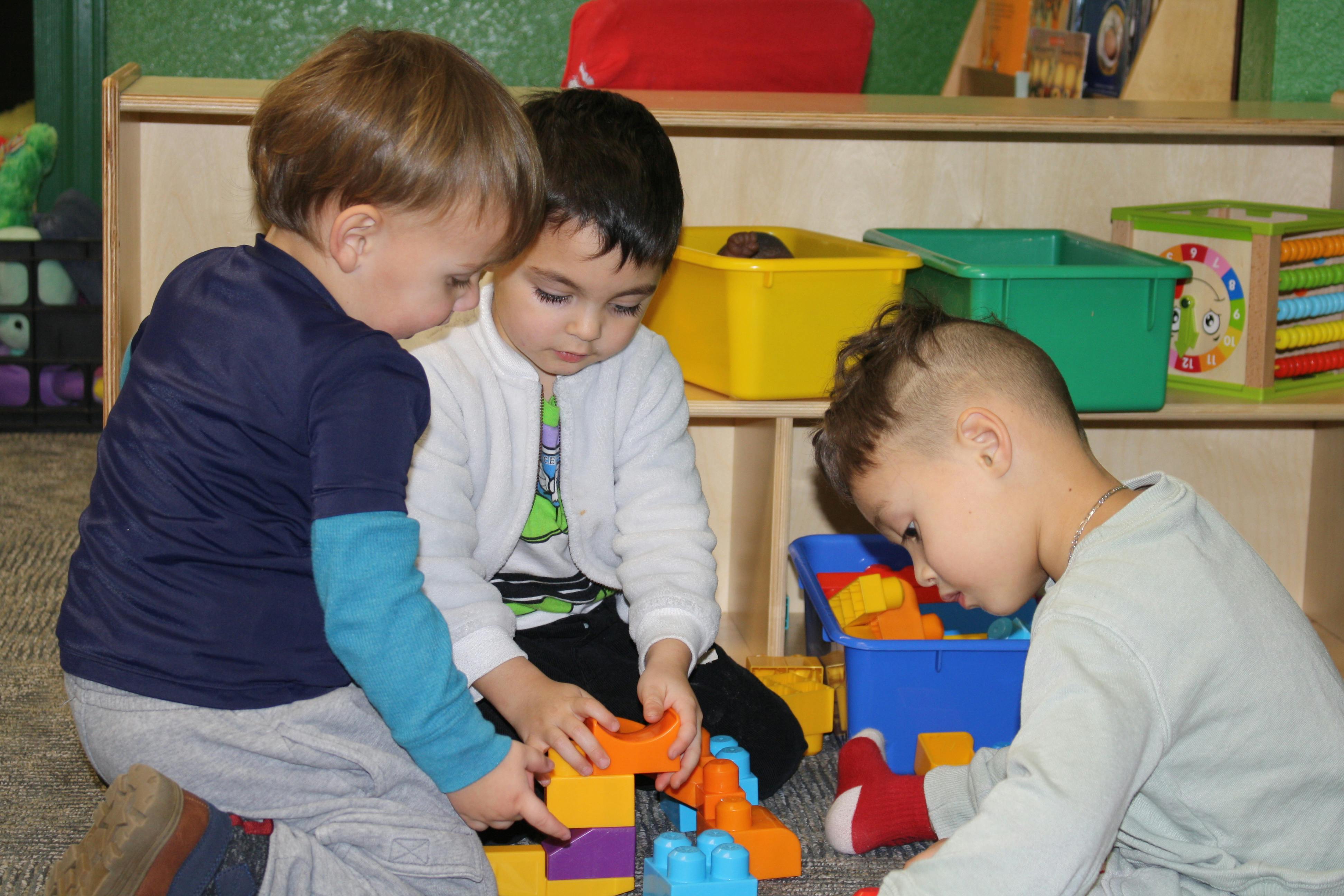 Three children playing with colorful building blocks