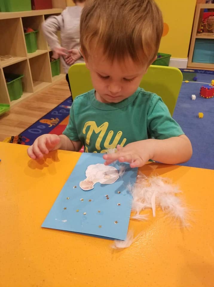 Child making a craft with feathers and paper