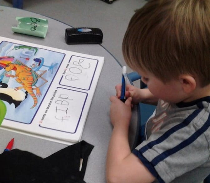 Child writing on a worksheet at a table