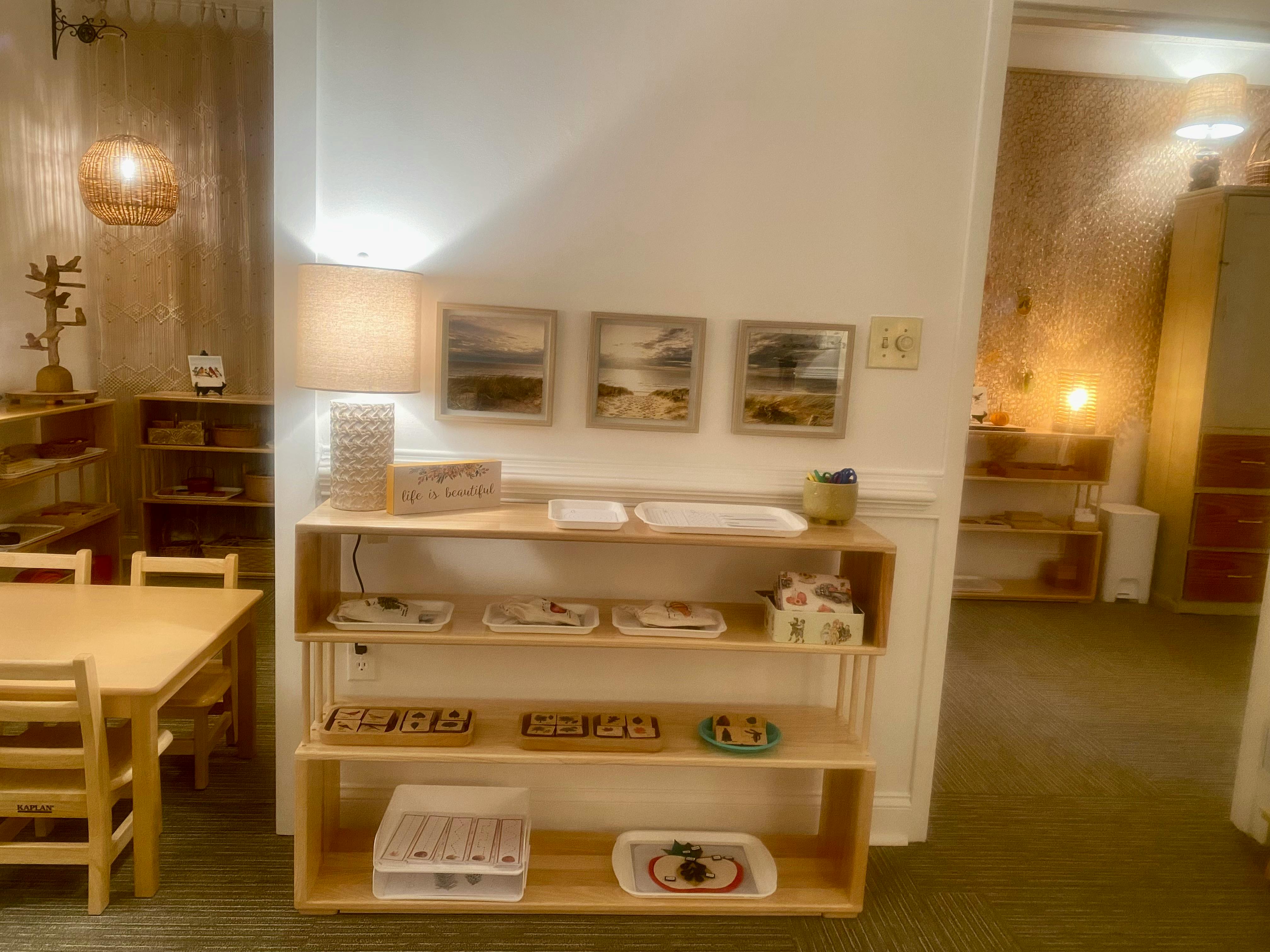 Classroom with wooden shelves holding learning materials and a table with chairs