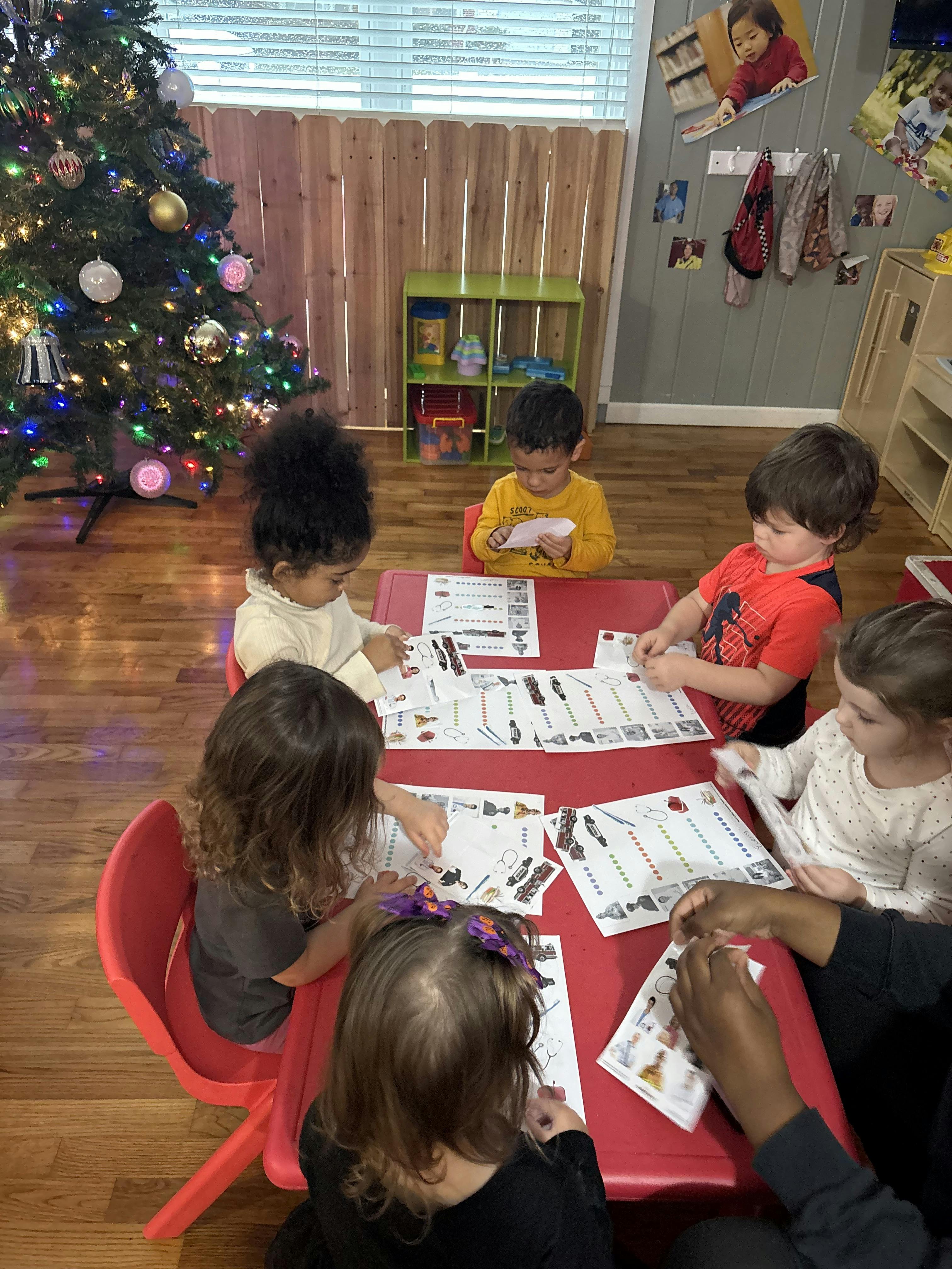 Children sitting at a red table doing an activity