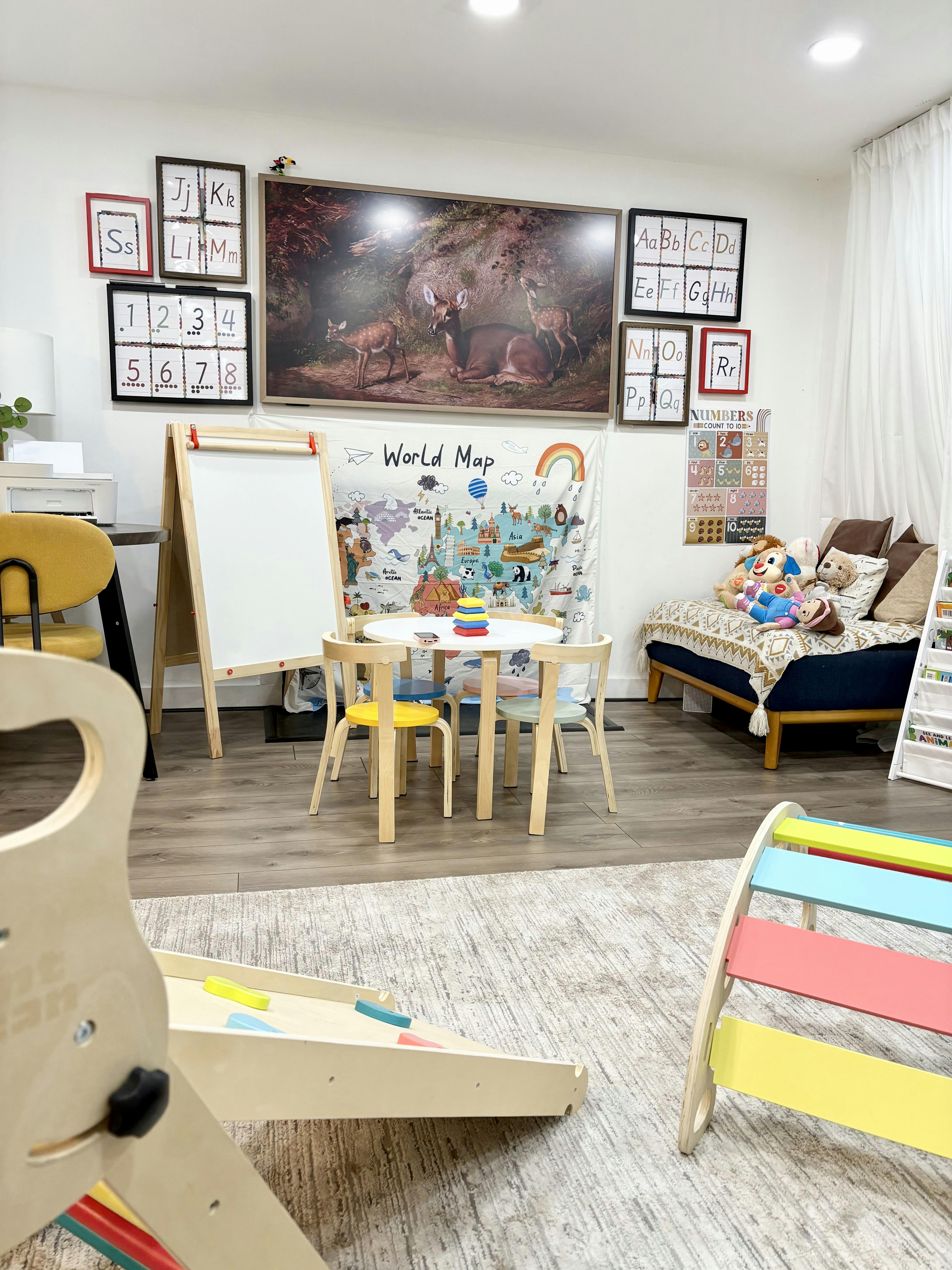 Children's play area with small table and chairs, easel, and world map