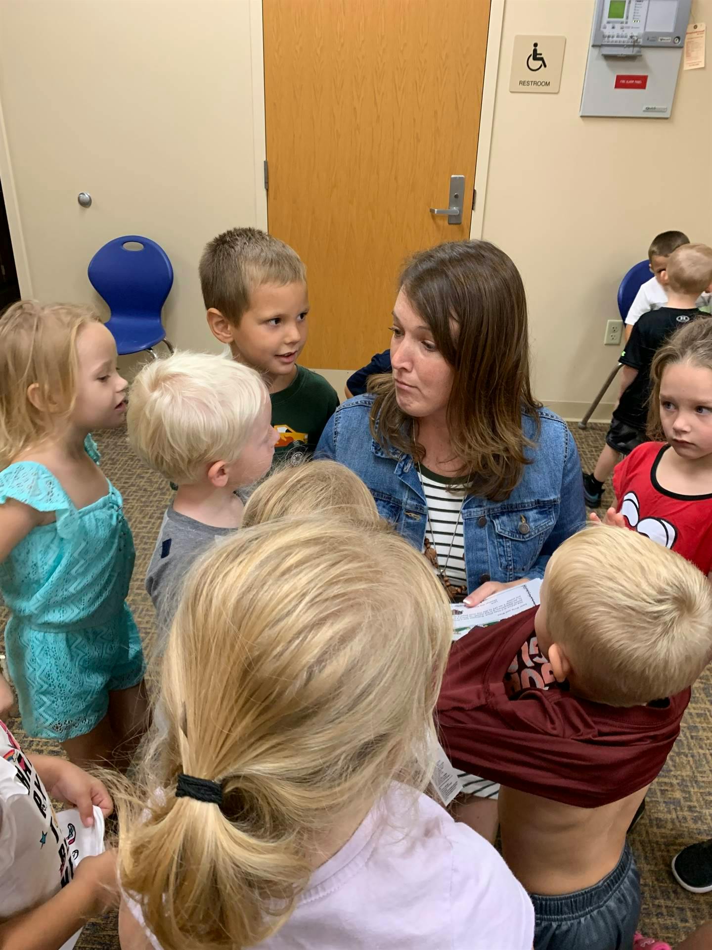 Adult person sitting on floor surrounded by children