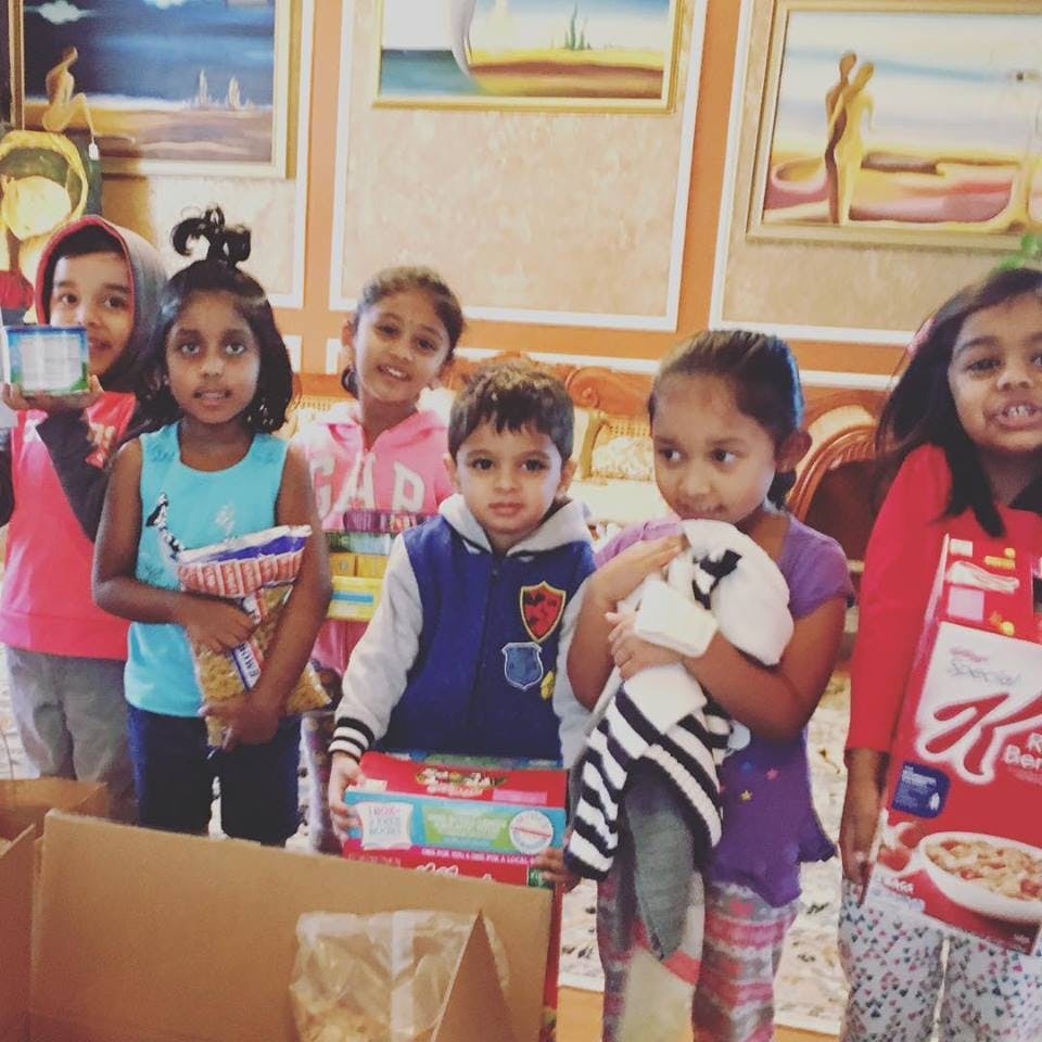 Group of children standing around cardboard boxes with items