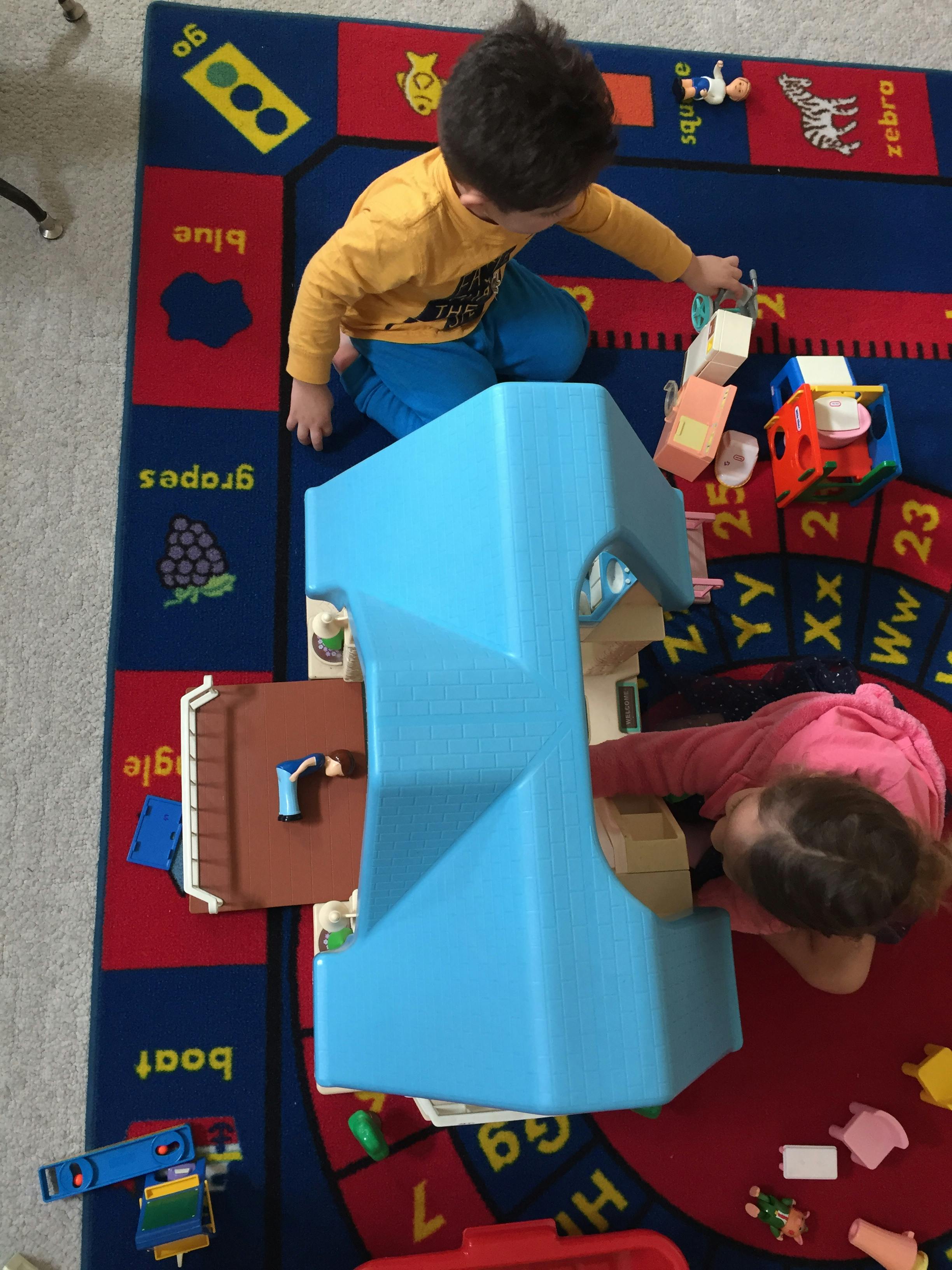 Two children playing with toys on a colorful rug