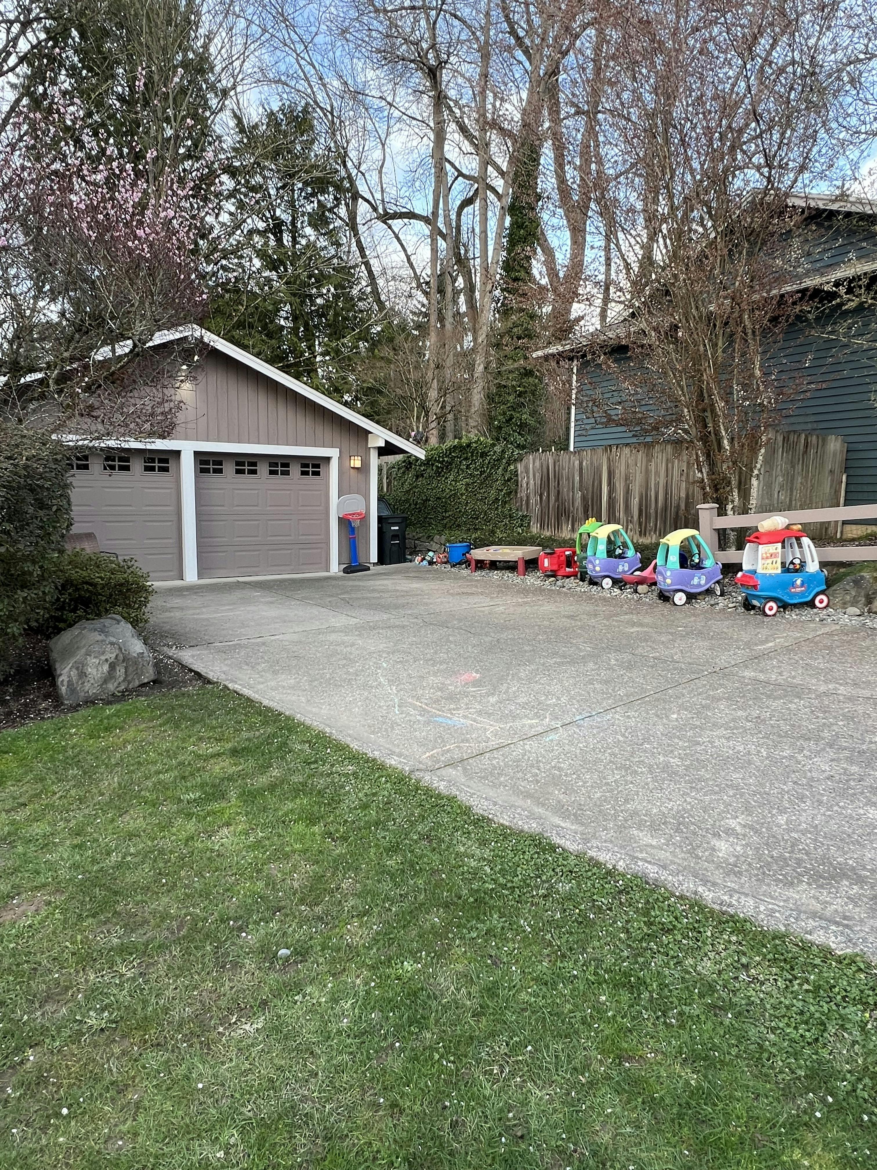 A driveway with a garage and several toy cars lined up