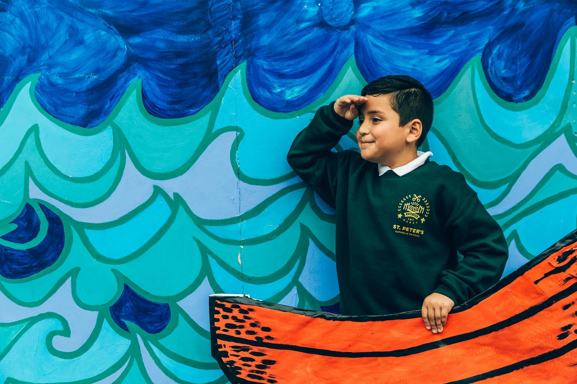 Child in a boat-shaped cutout with arm raised to forehead, looking out