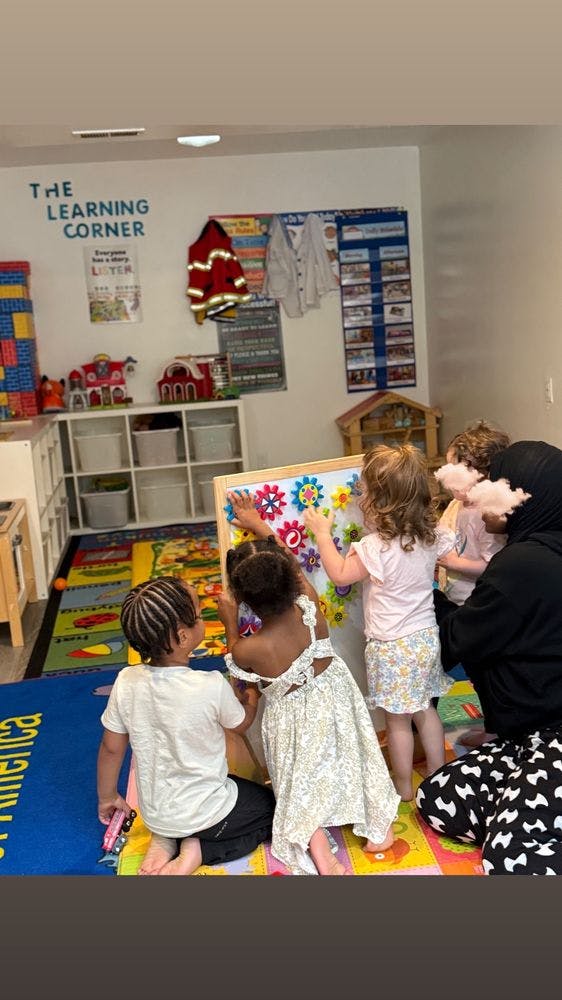 Children and an adult playing with a gear board in a classroom