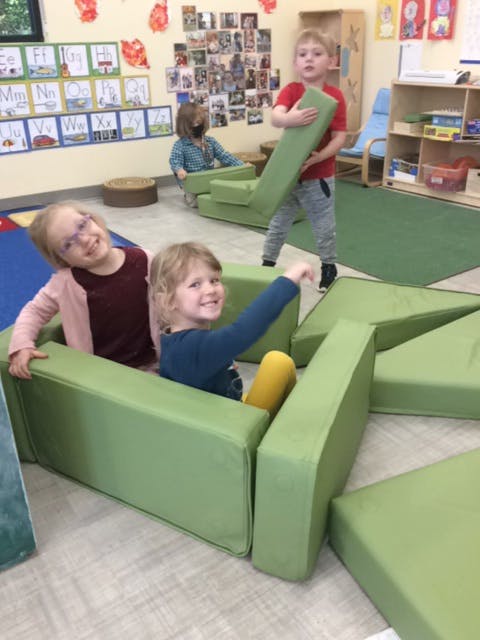 Children playing with green foam blocks in a classroom
