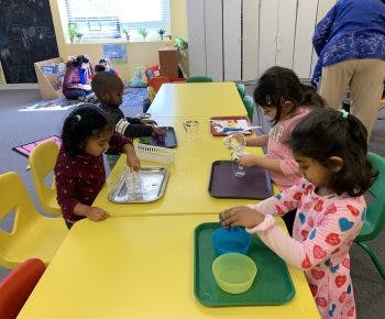 Children at yellow tables engaged in activities