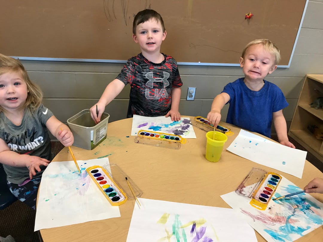 Three children painting at a table