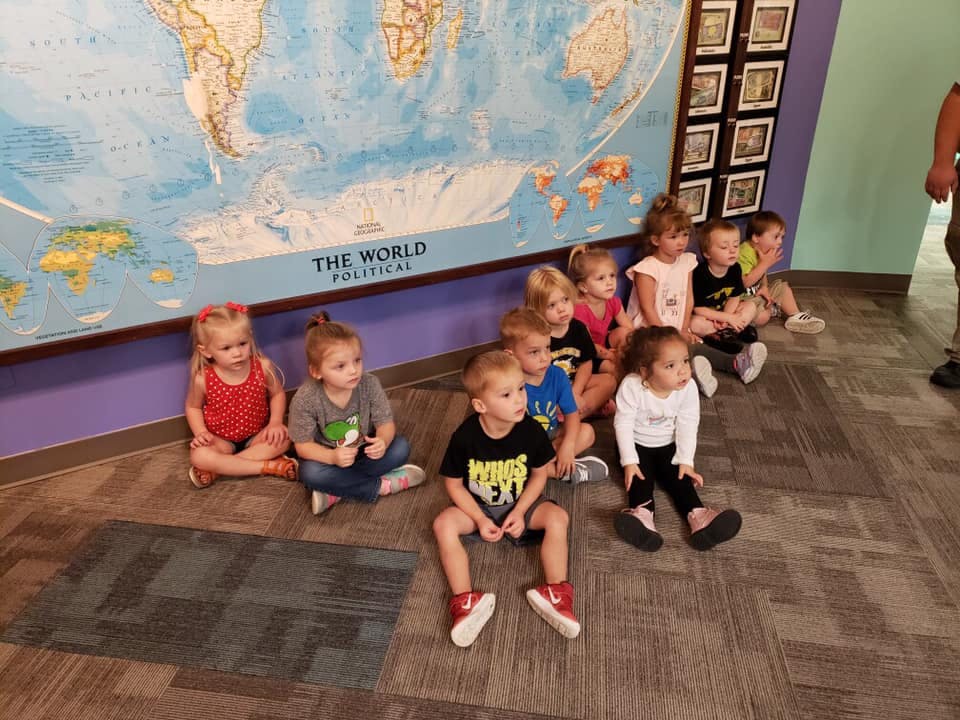 Group of children sitting on the floor in front of a large world map