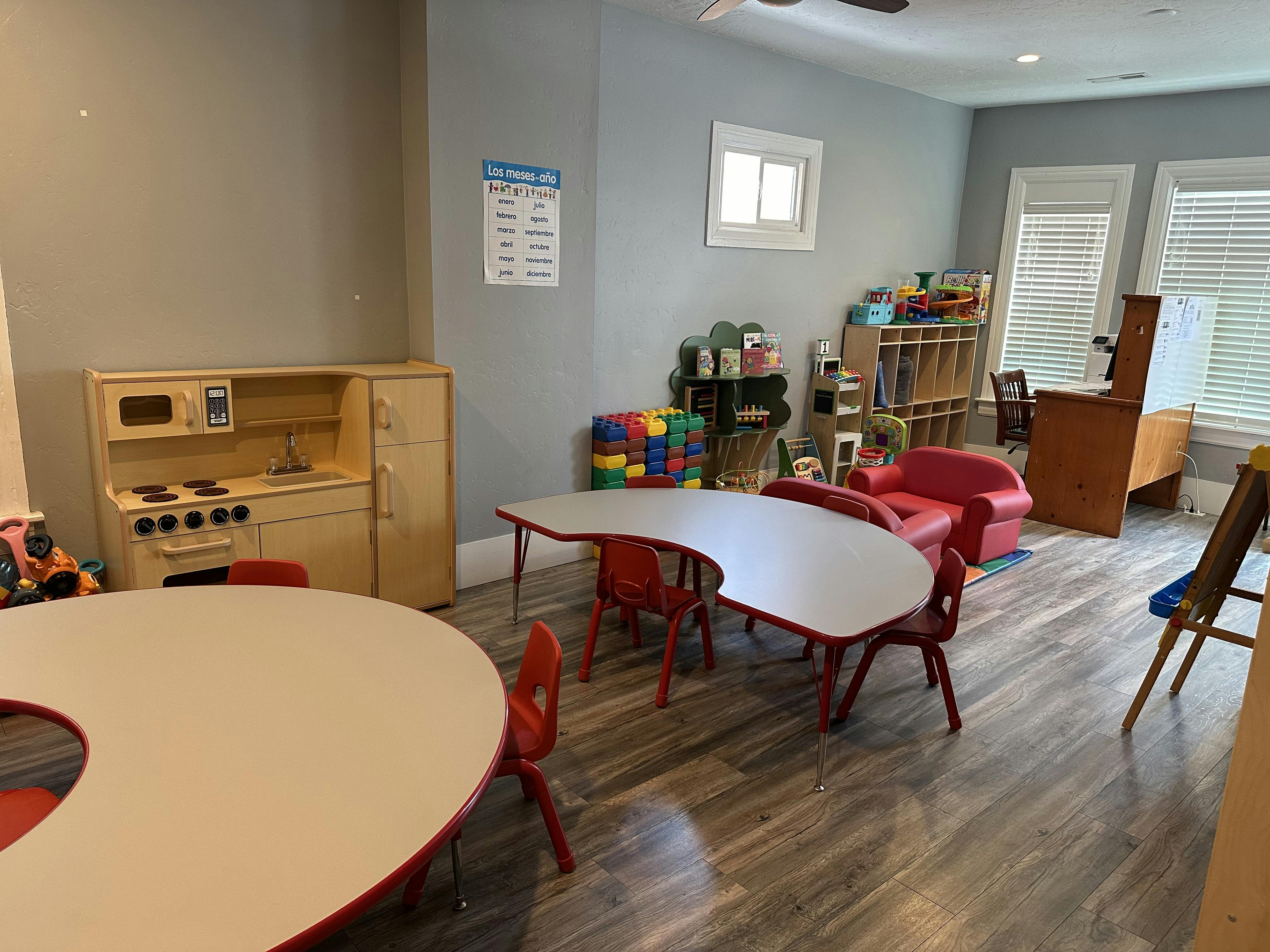 Playroom with child-sized tables and chairs, toy kitchen, and shelves of shelves with shelves
