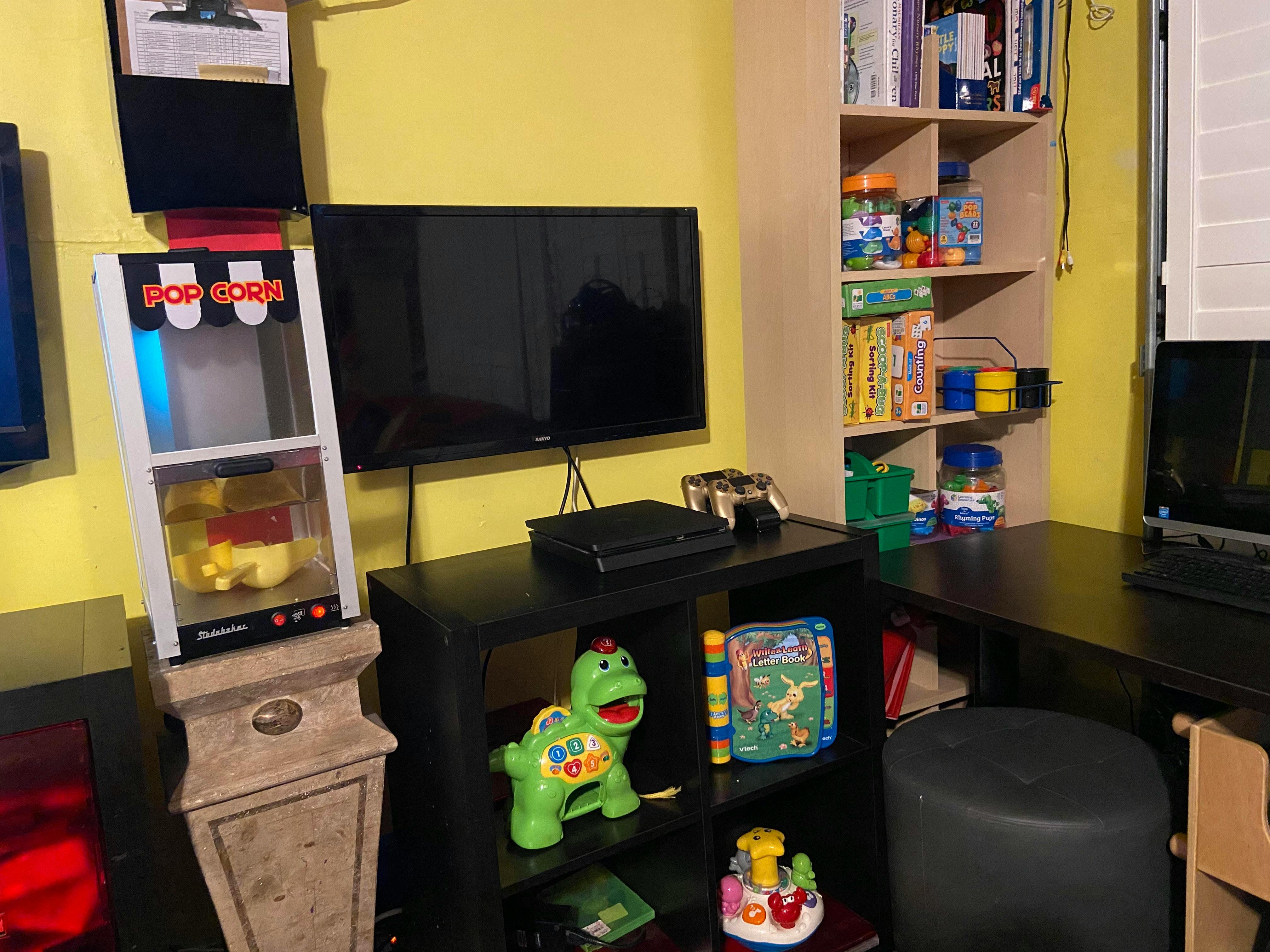 Popcorn machine next to a television and shelves with toys