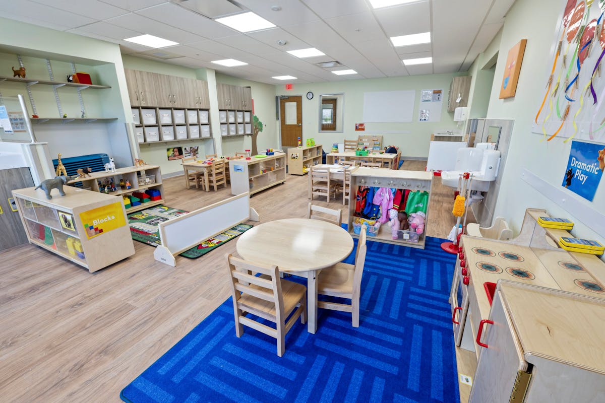 Classroom with child-sized tables and chairs, shelves, and play areas