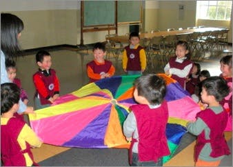 Children playing with a colorful parachute