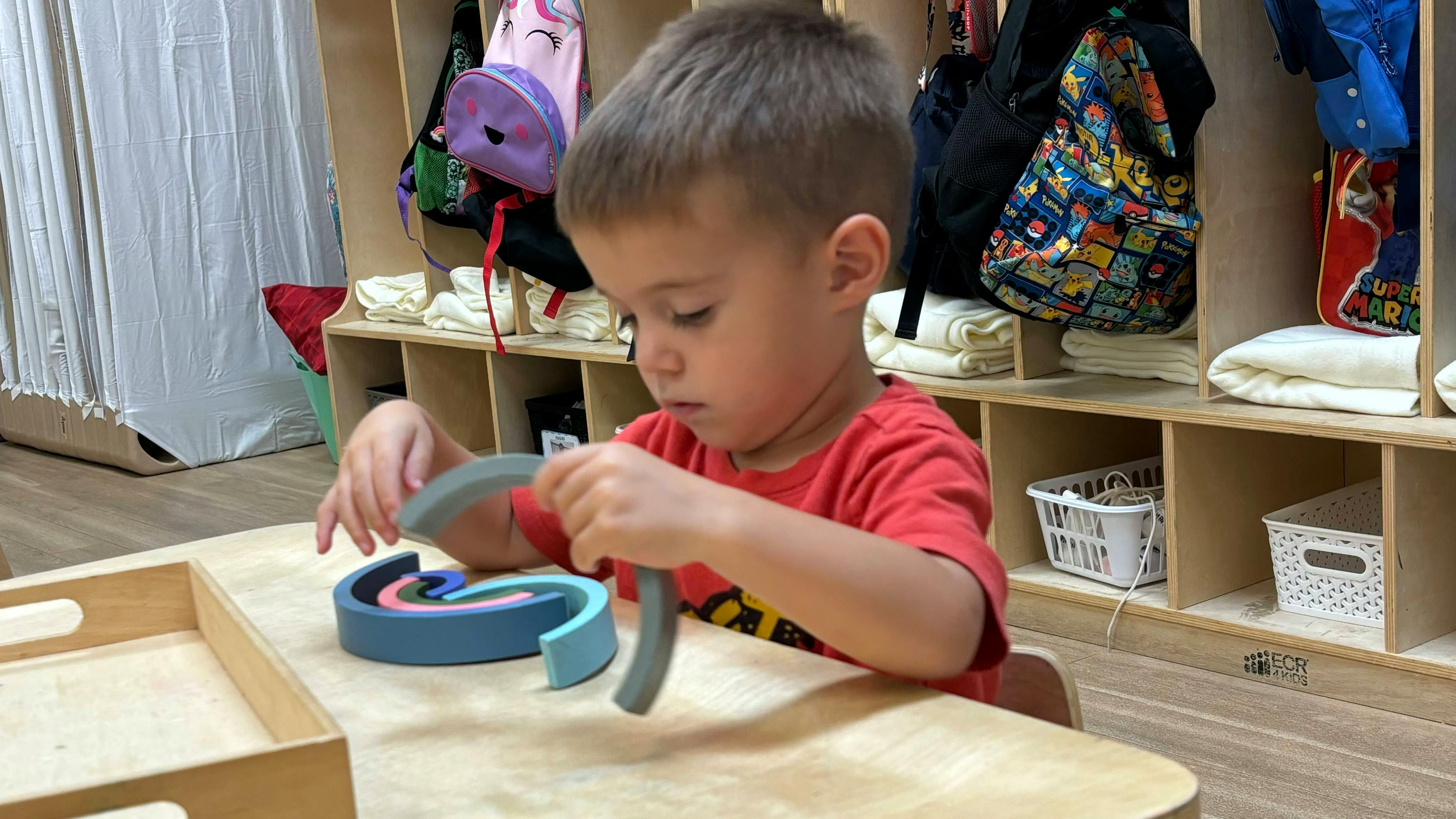 Child playing with a colorful wooden toy on a table