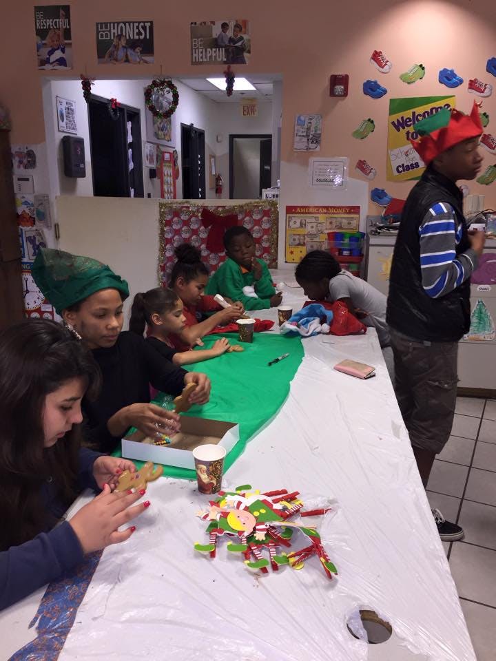 Children and teens decorating gingerbread cookies at a long table