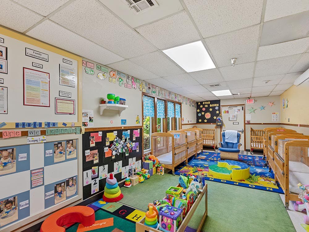 daycare classroom with multiple cribs and play areas