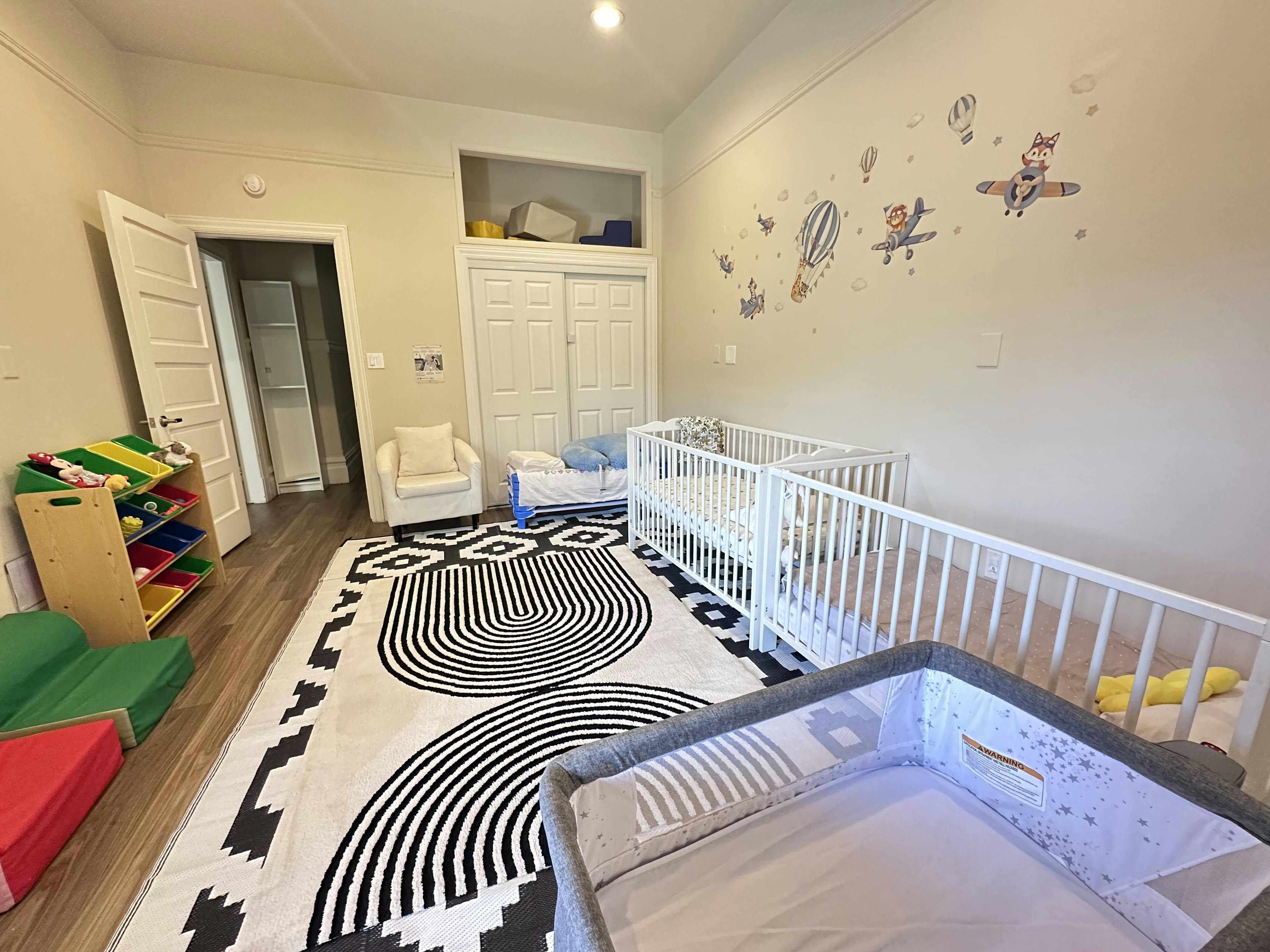 Cribs in a child care room with a play mat and toy organizer