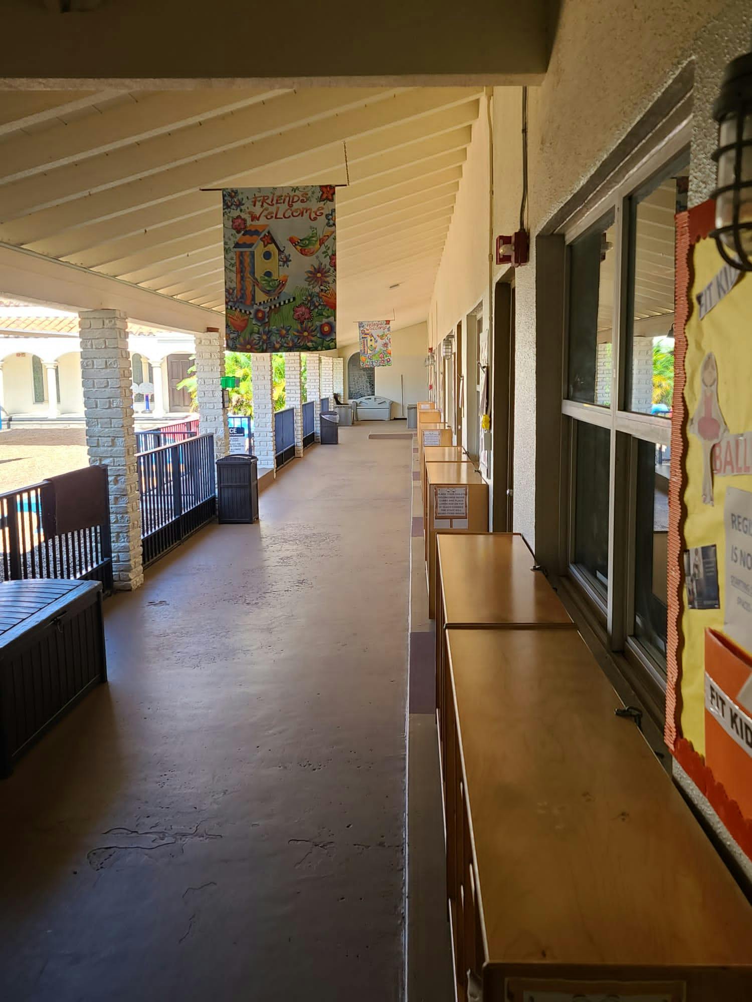 Outdoor school hallway with classrooms on one side and a railing on the other